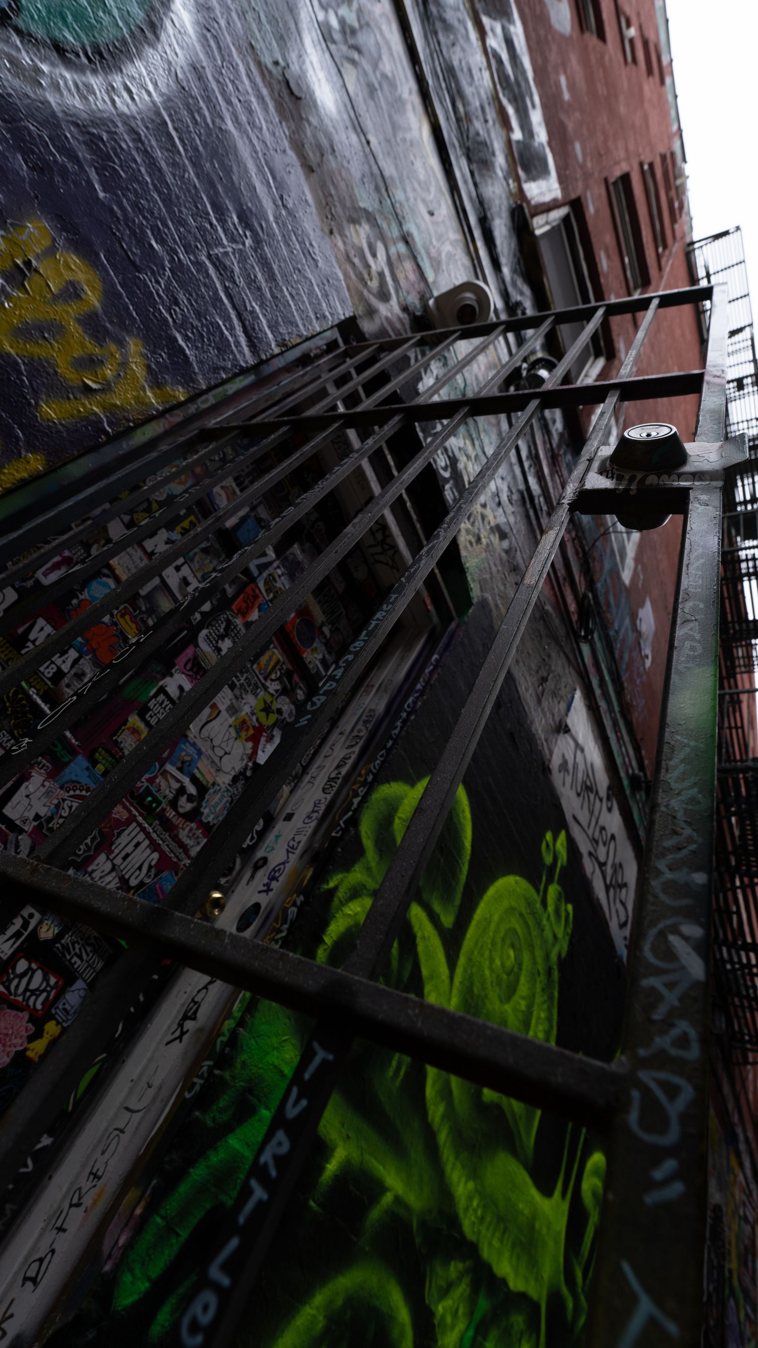 Dark urban alley with green graffiti visible on the walls.