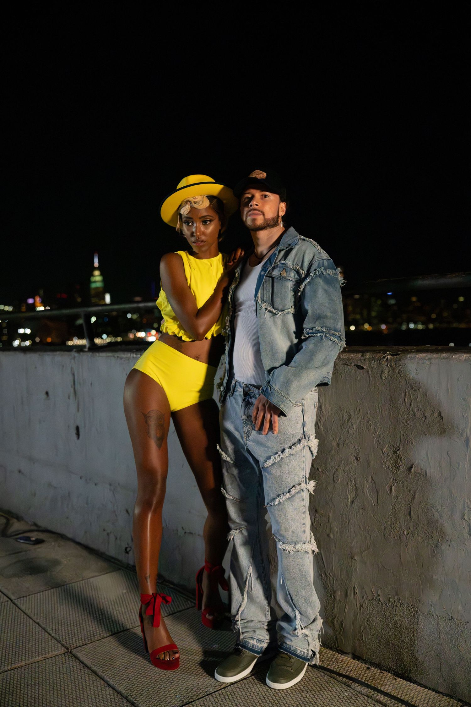 Nighttime rooftop fashion shoot with yellow outfit and denim styling.