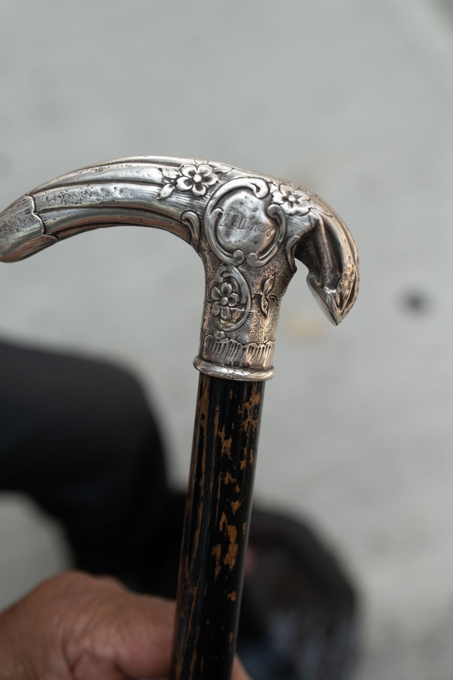 Ornate silver walking cane handle with detailed metalwork showing a decorative bird design.