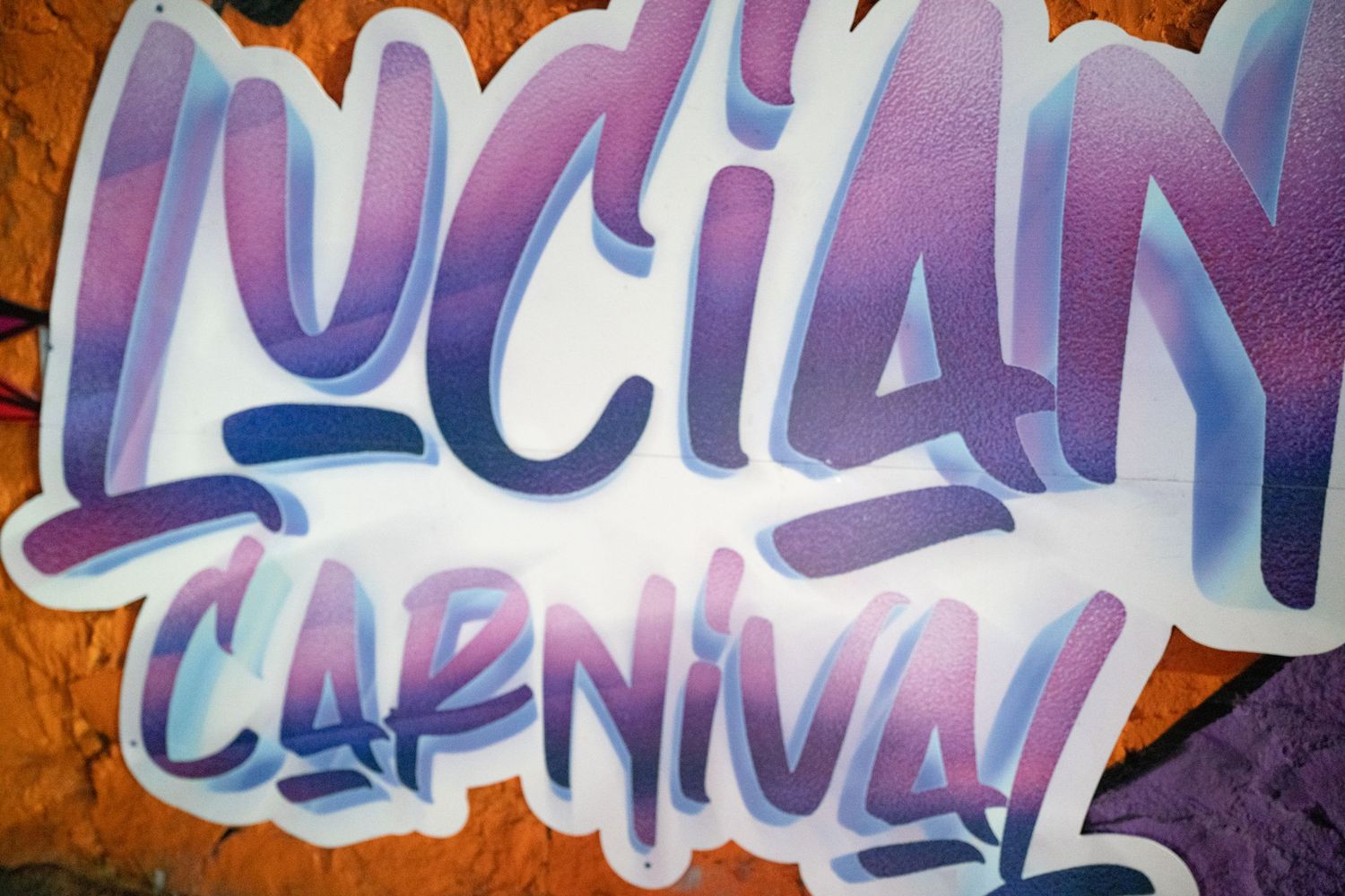 Colorful graffiti text art painted on an orange wall with purple and white tones.