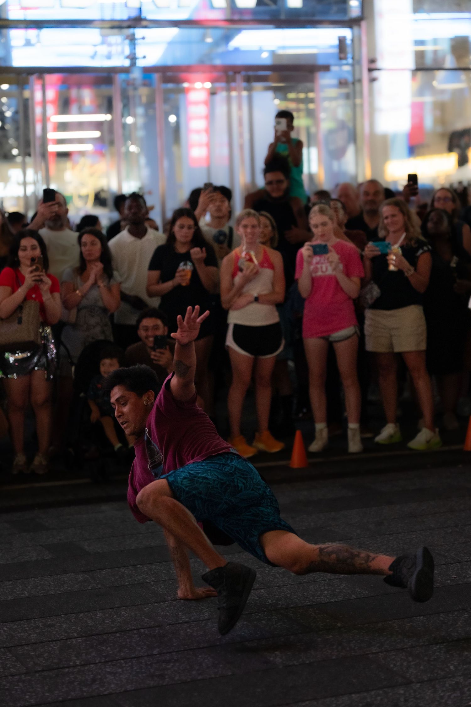 Street dancer performing an acrobatic move in front of a crowd at night.