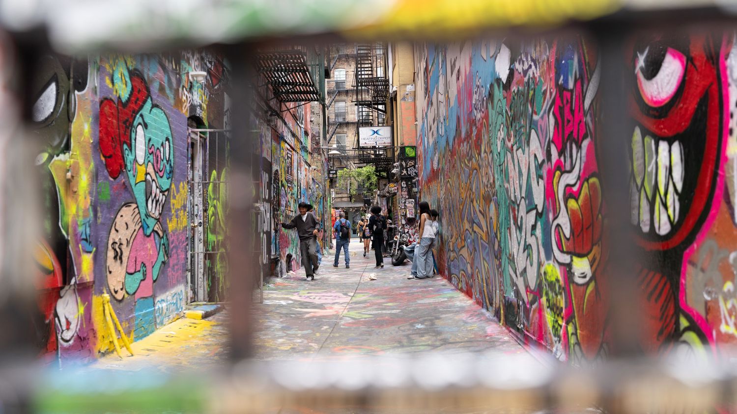 Long corridor with vibrant street art and graffiti murals covering both walls.