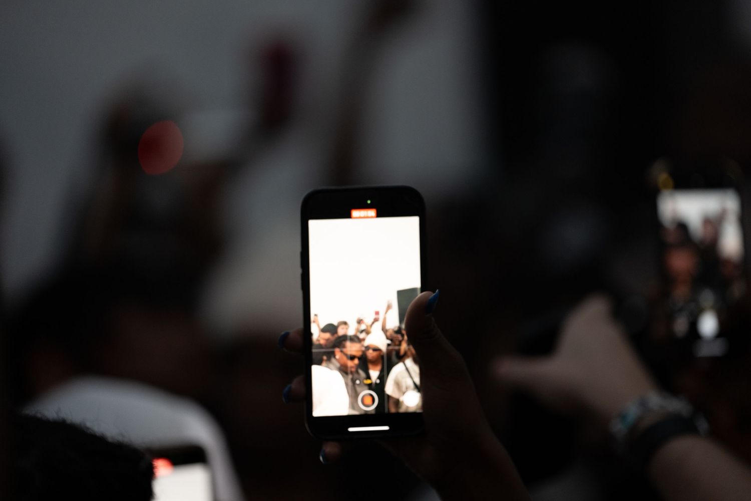 Dark event space with glowing phone screens visible in the background.