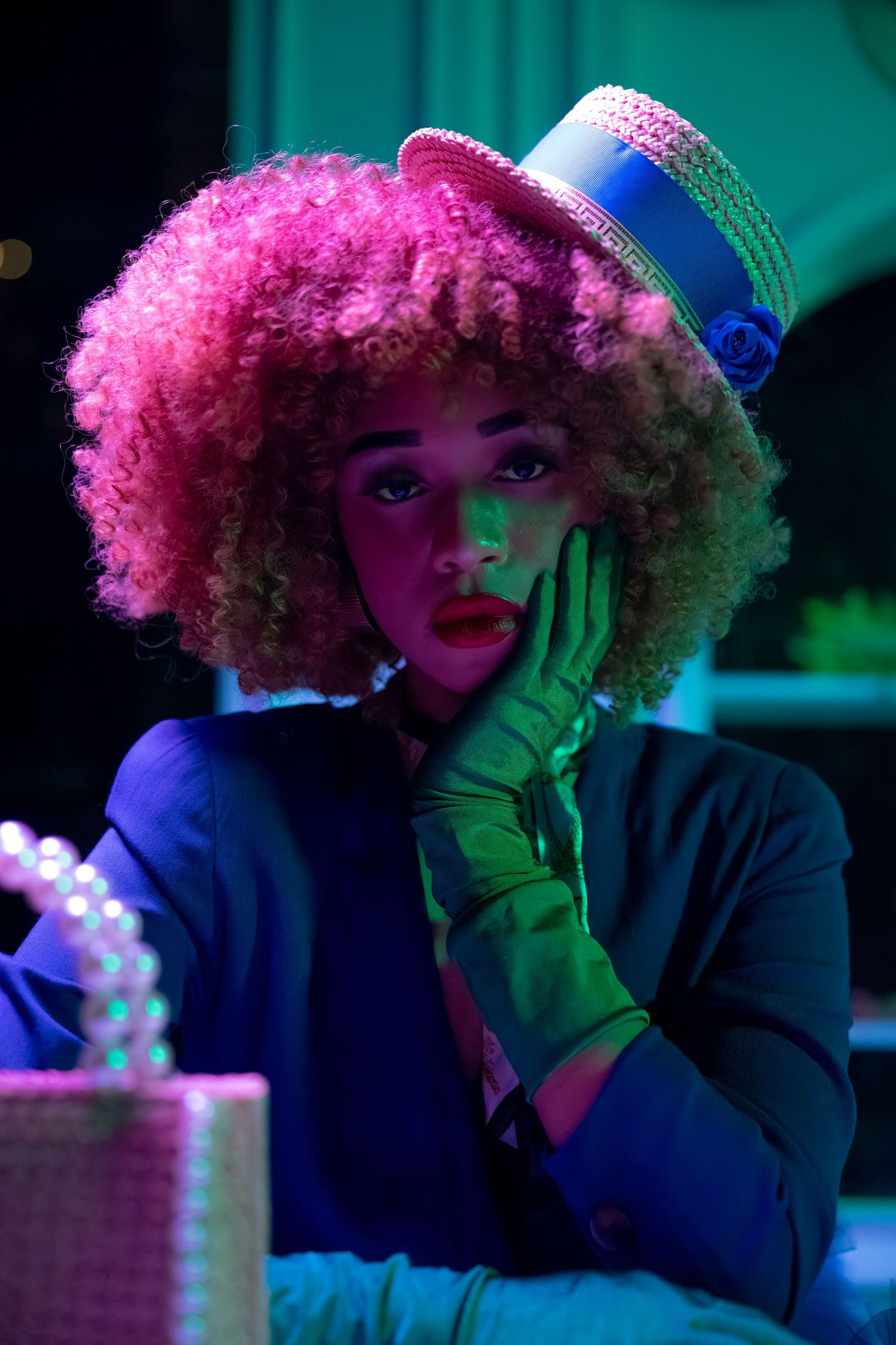 Fashion portrait with vibrant curly hair under neon pink and blue lighting.