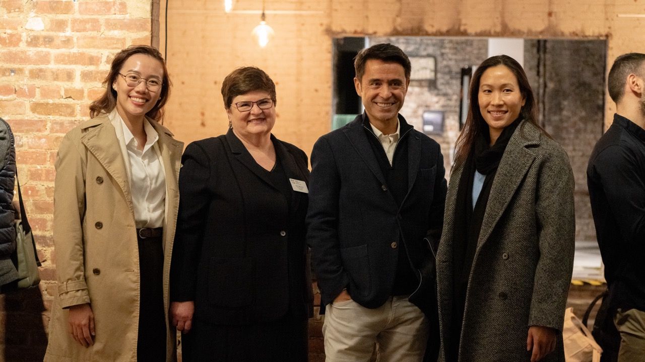 Group of professionals gathered for networking event in brick-walled venue.
