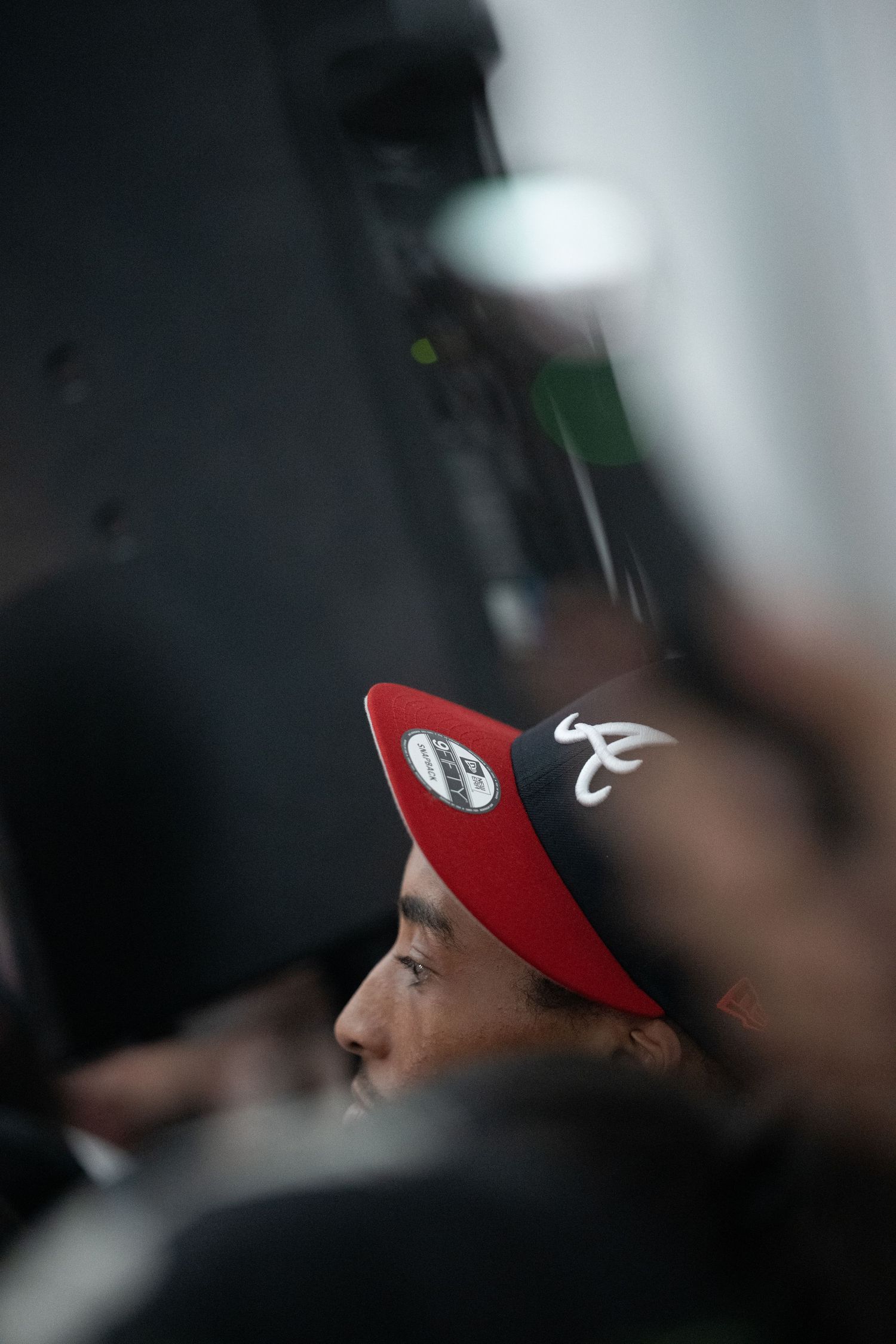 A red baseball cap with a white logo is shown in profile against a dark background.