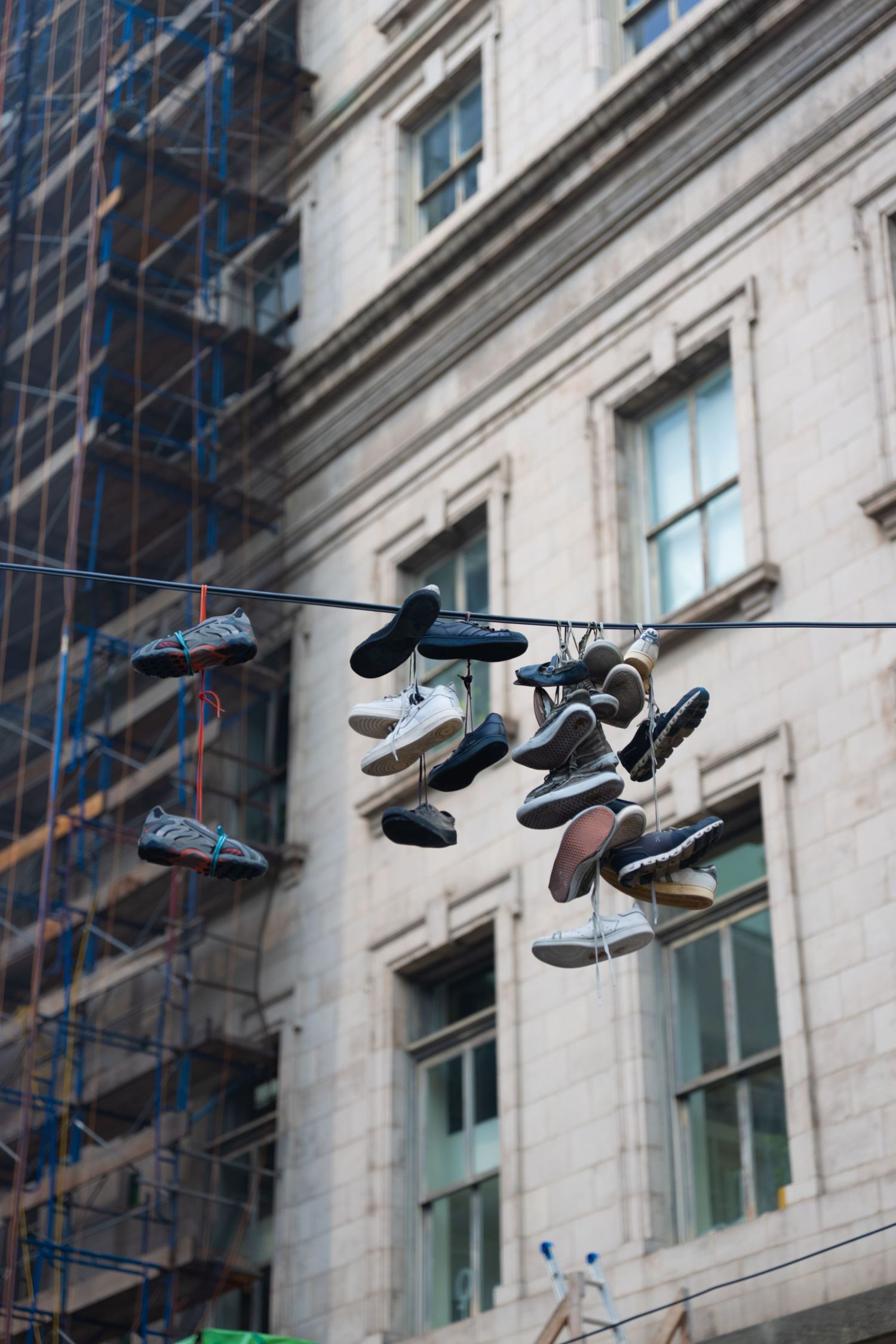 Sneakers hanging from power lines against urban building backdrop.