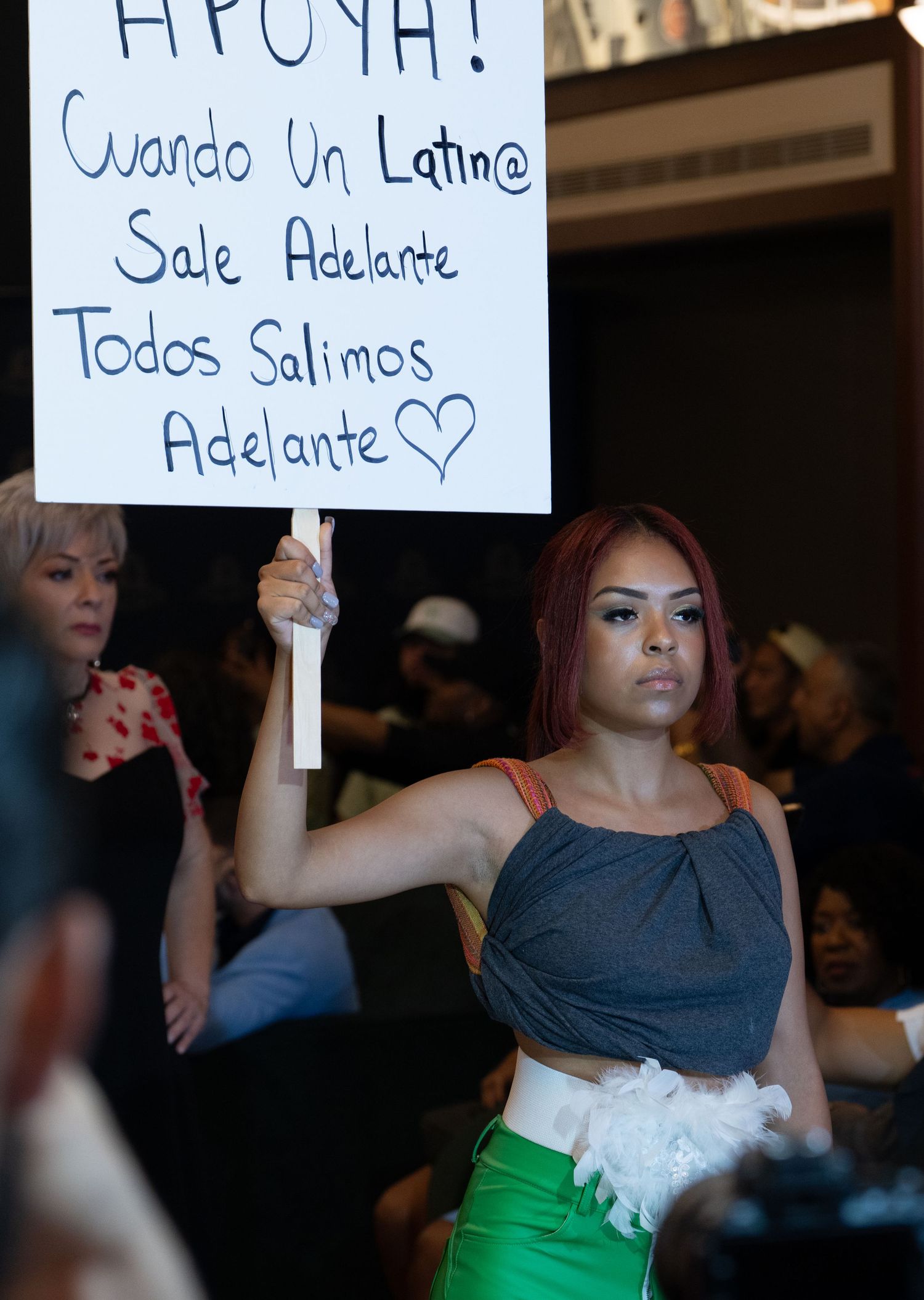 Audience members hold up handwritten signs during a performance event.