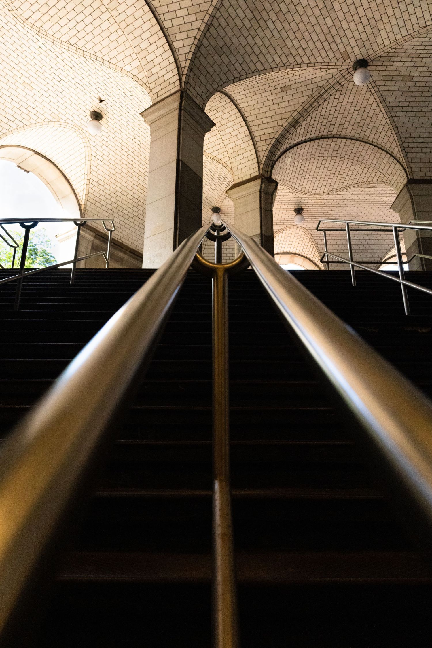 Modern architectural interior featuring curved arches and metal railings in dramatic lighting.
