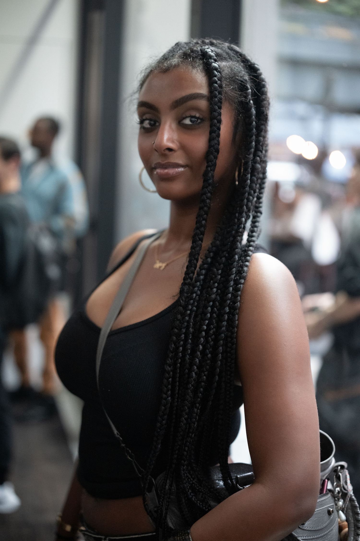 Woman in black outfit with long braided hair poses for photos.