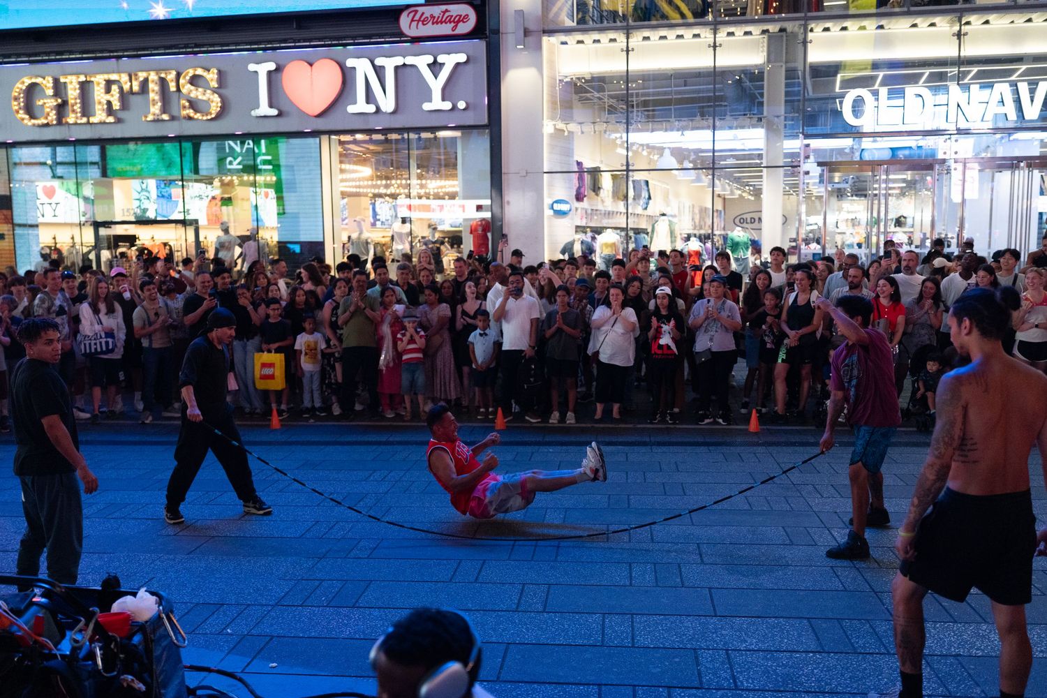 Street performers entertaining crowds outside a souvenir shop in Times Square at night.