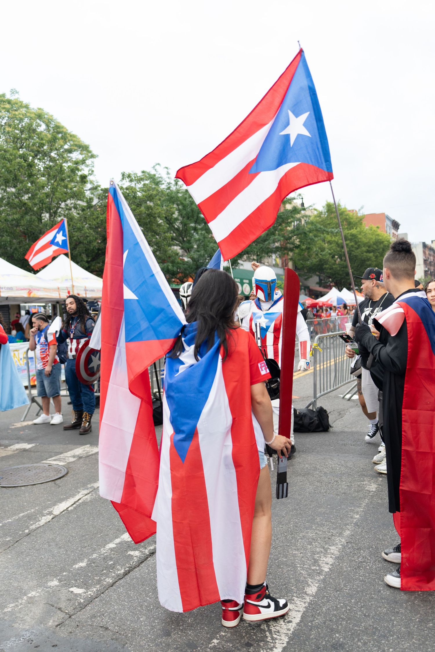 Multiple Puerto Rican flags wave in the breeze during a street celebration.
