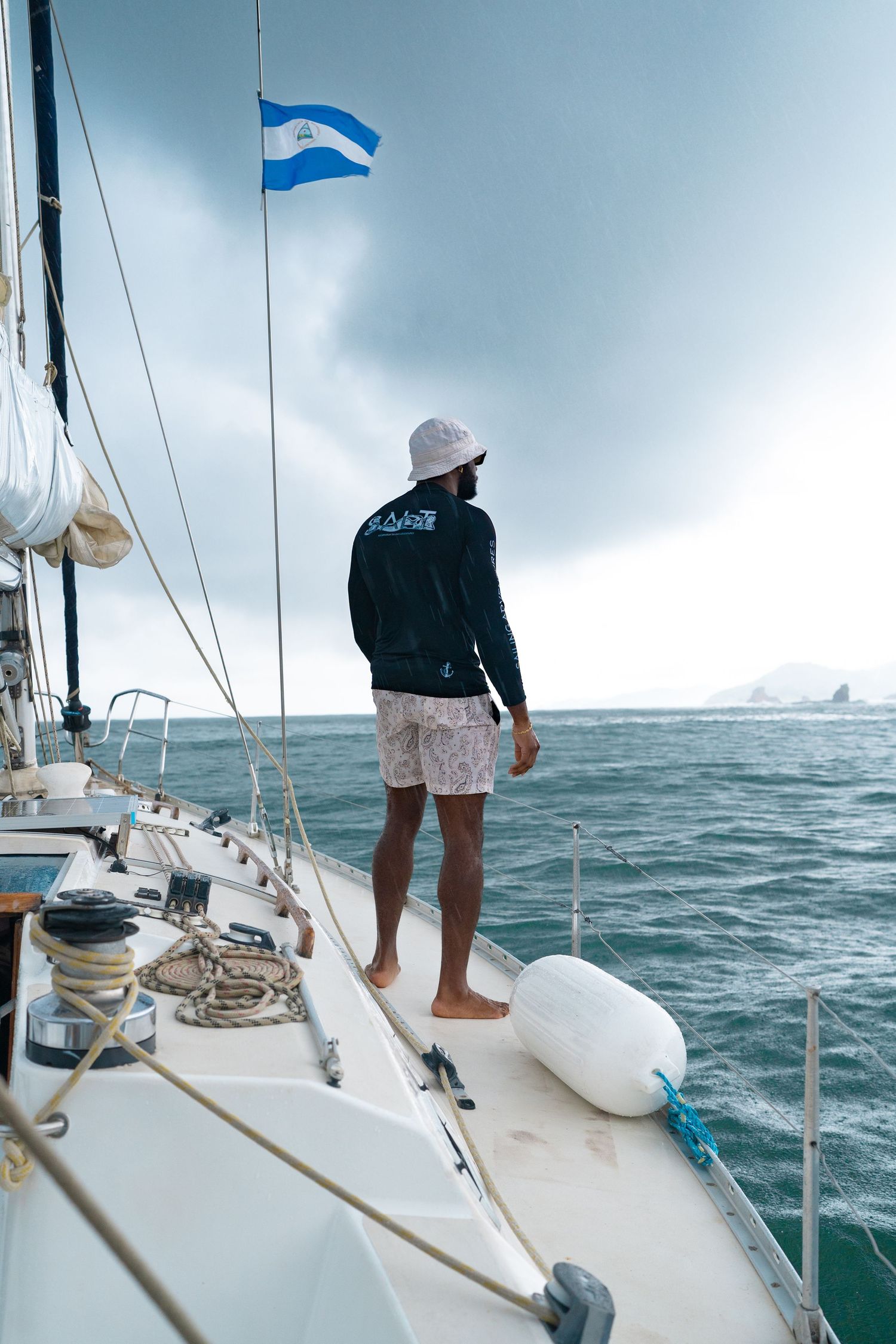 Sailing yacht on choppy waters with Nicaraguan flag flying under cloudy skies.