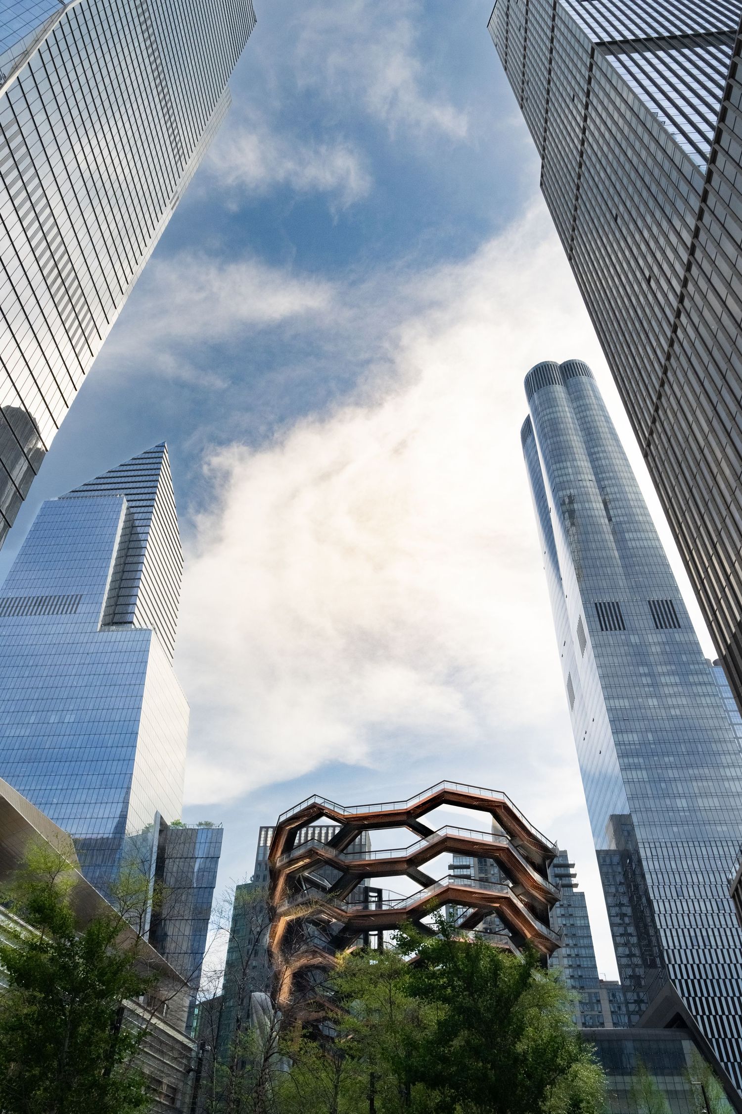 Modern glass skyscrapers reaching into blue sky with architectural detail below.