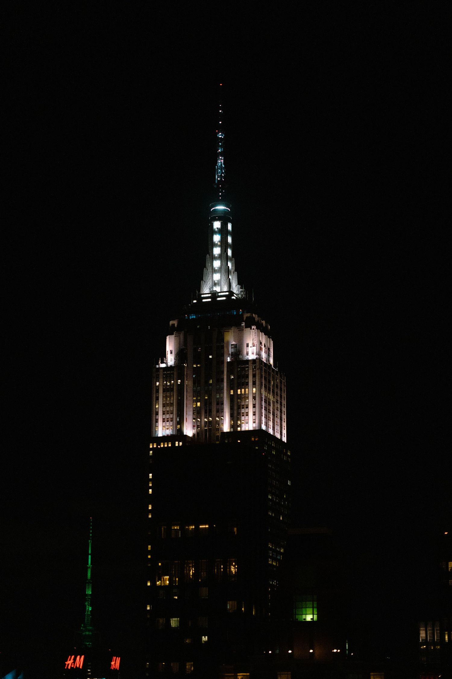 Empire State Building illuminated at night against dark sky.