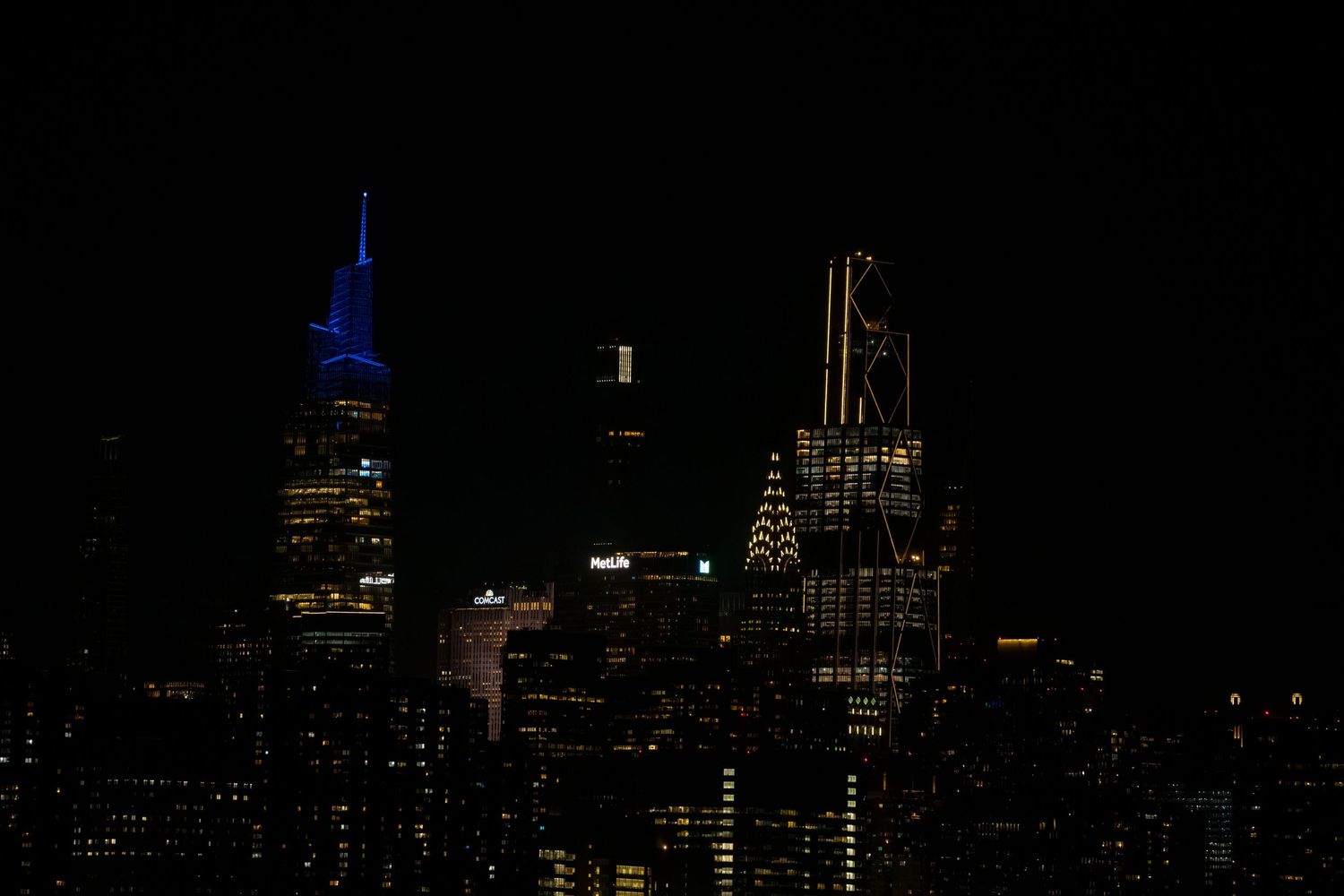 Illuminated city skyline at night with prominent skyscrapers against a dark sky.