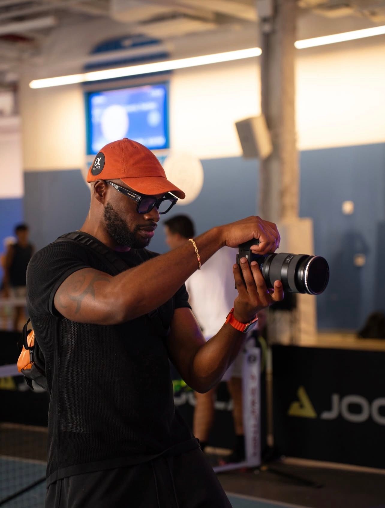 A photographer in a black shirt and orange hat captures action shots in a sequence of four connected images.