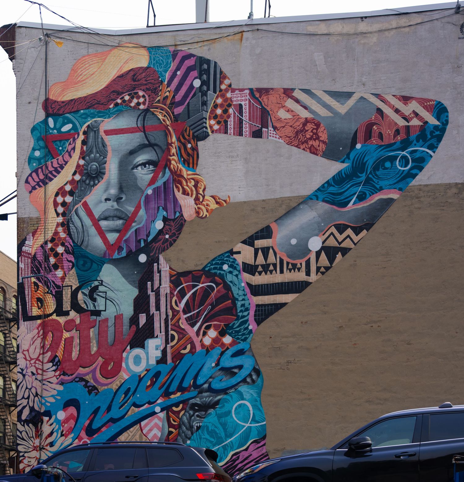 Abstract graffiti mural in blue and pink tones on concrete wall.