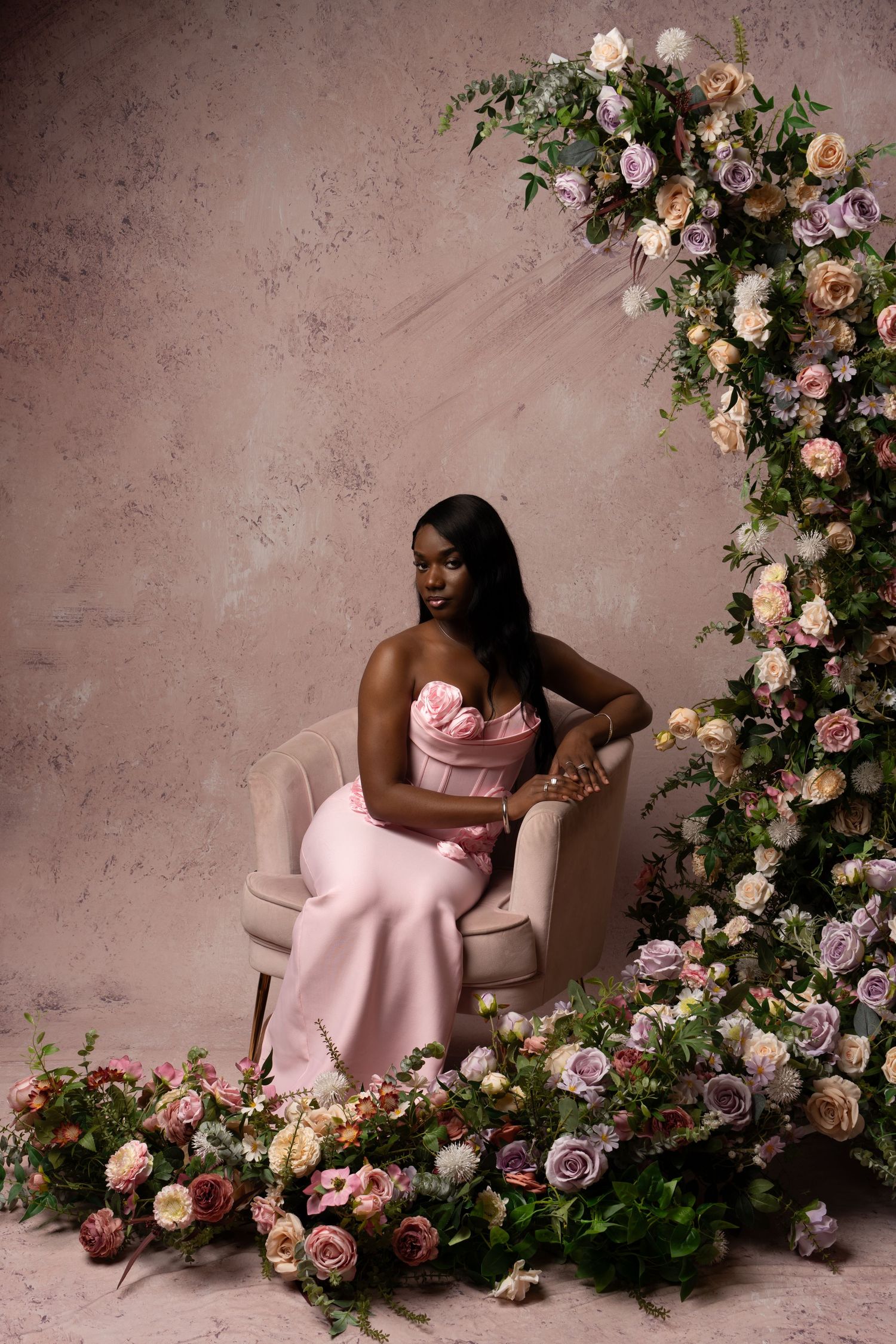 Elegant portrait series with pink dress and floral arch creating soft romantic atmosphere.