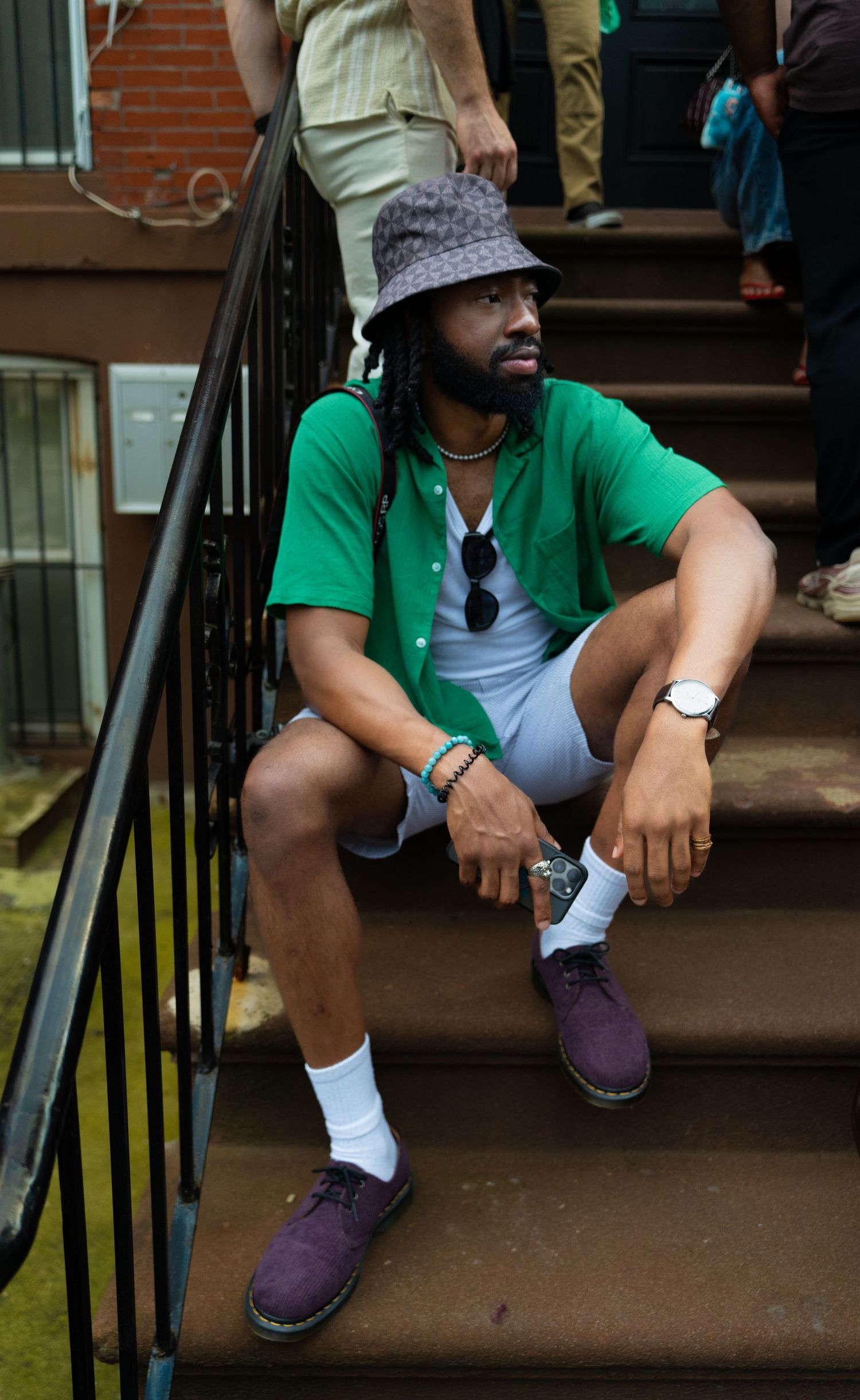 Person wearing purple Doc Martens boots and green shirt sitting on brownstone steps.