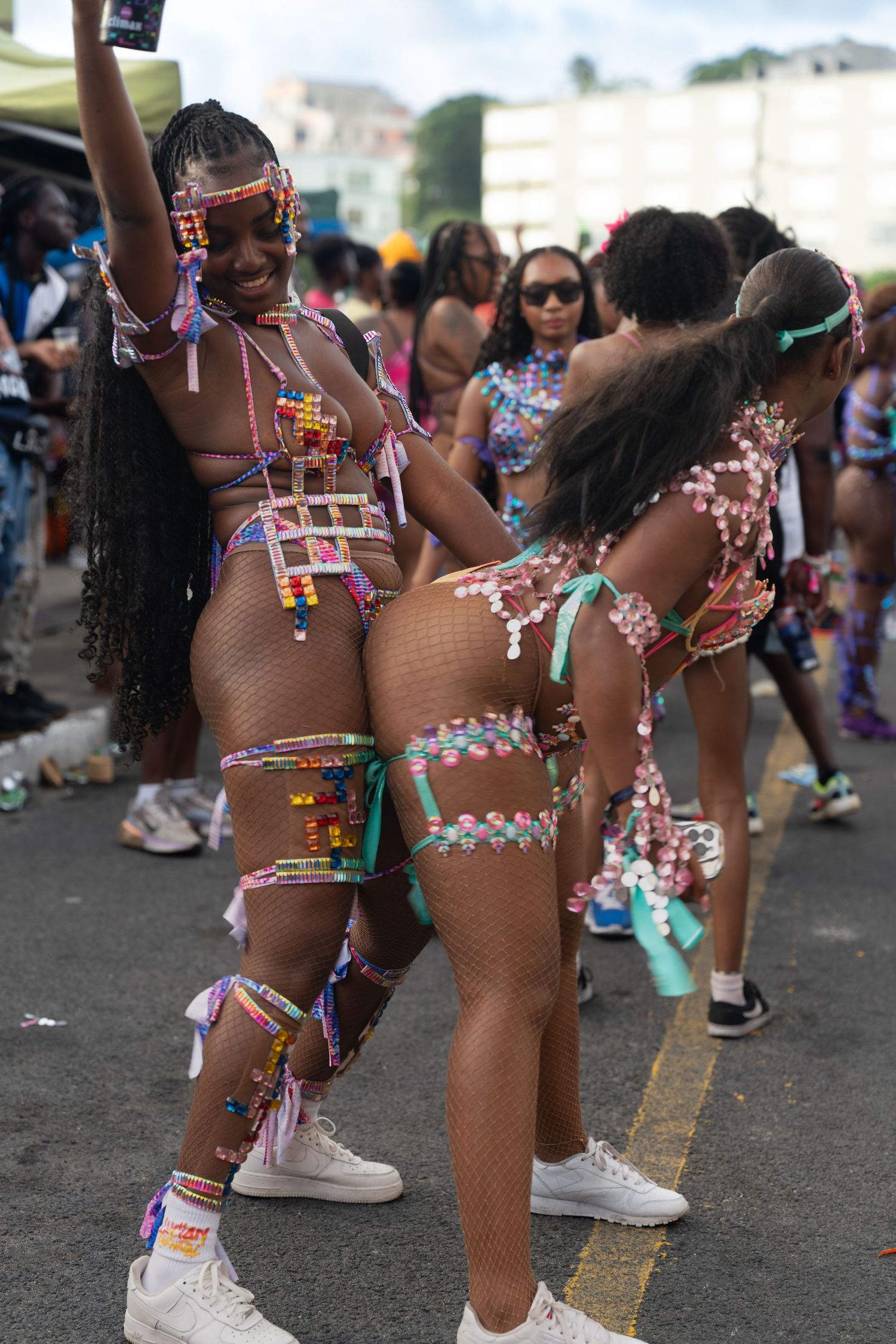 Carnival performers in ornate costumes and body jewelry dance in formation during a street festival.