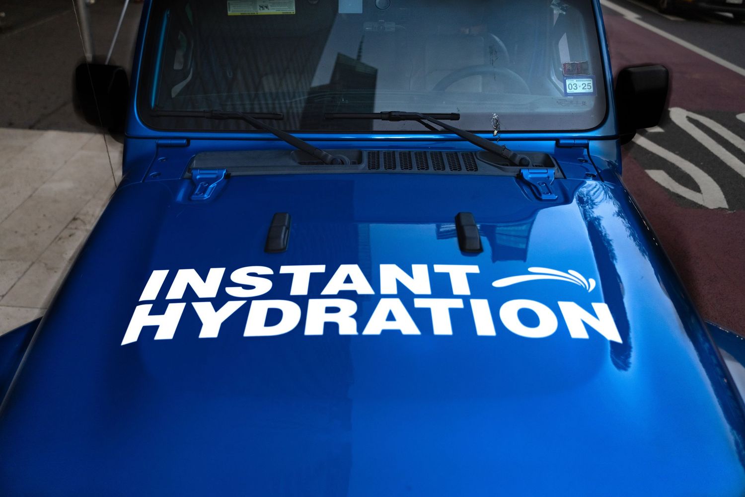 Close-up of a bright blue vehicle with 'Instant Hydration' branding on the hood.