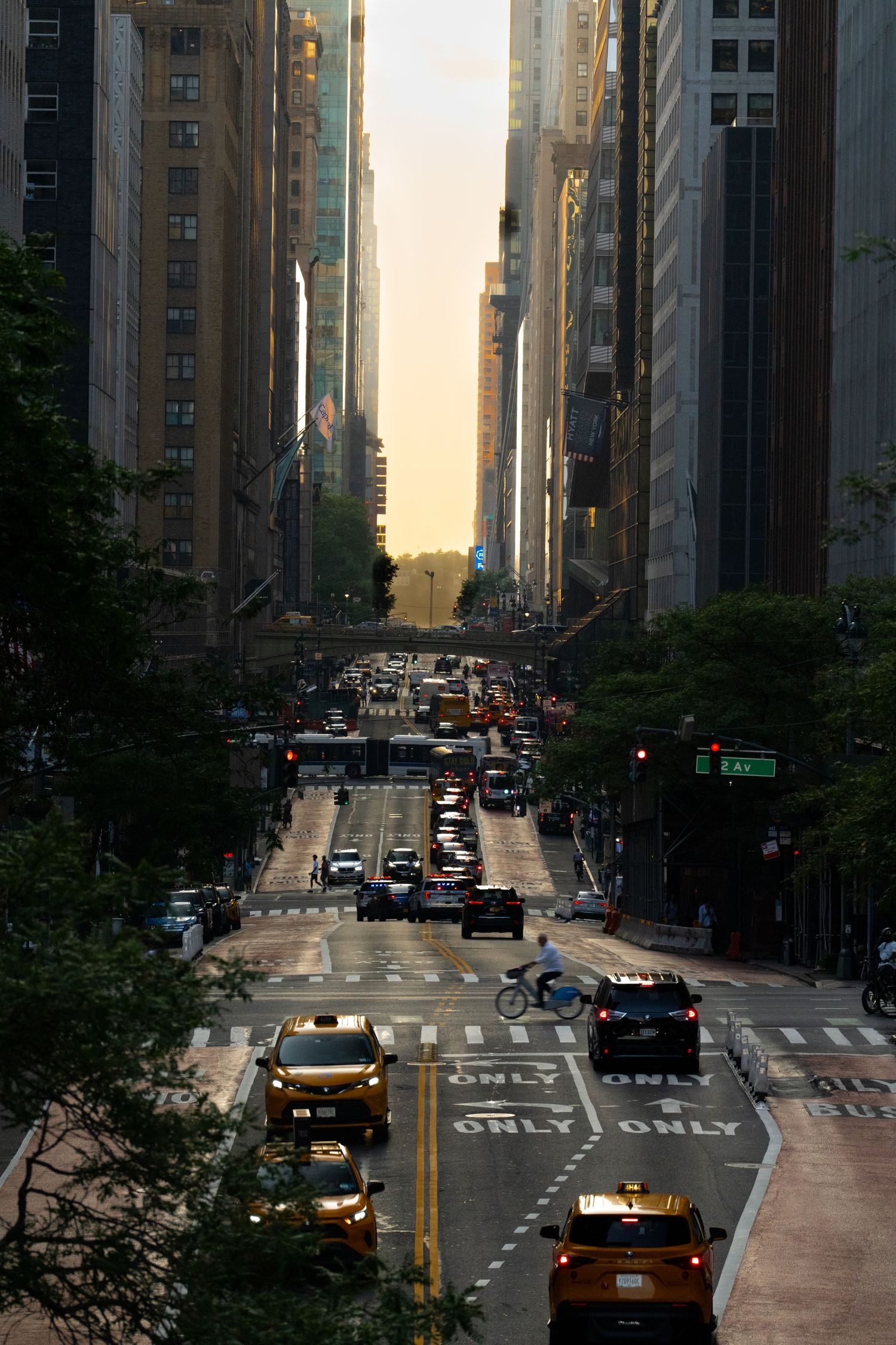 Urban street view of New York City with tall buildings and traffic during golden hour.