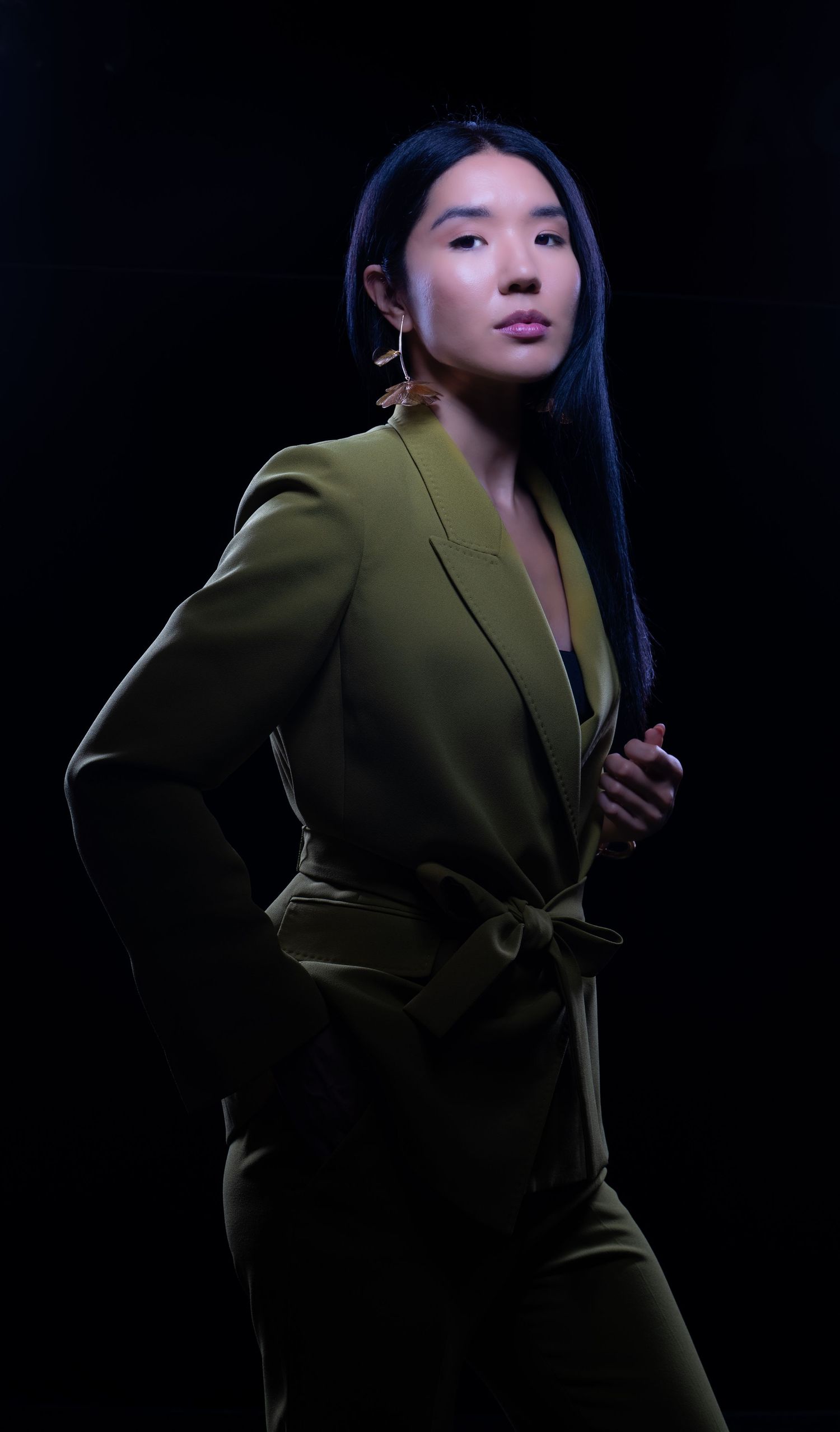 Fashion portrait with olive blazer in dramatic low-key lighting.