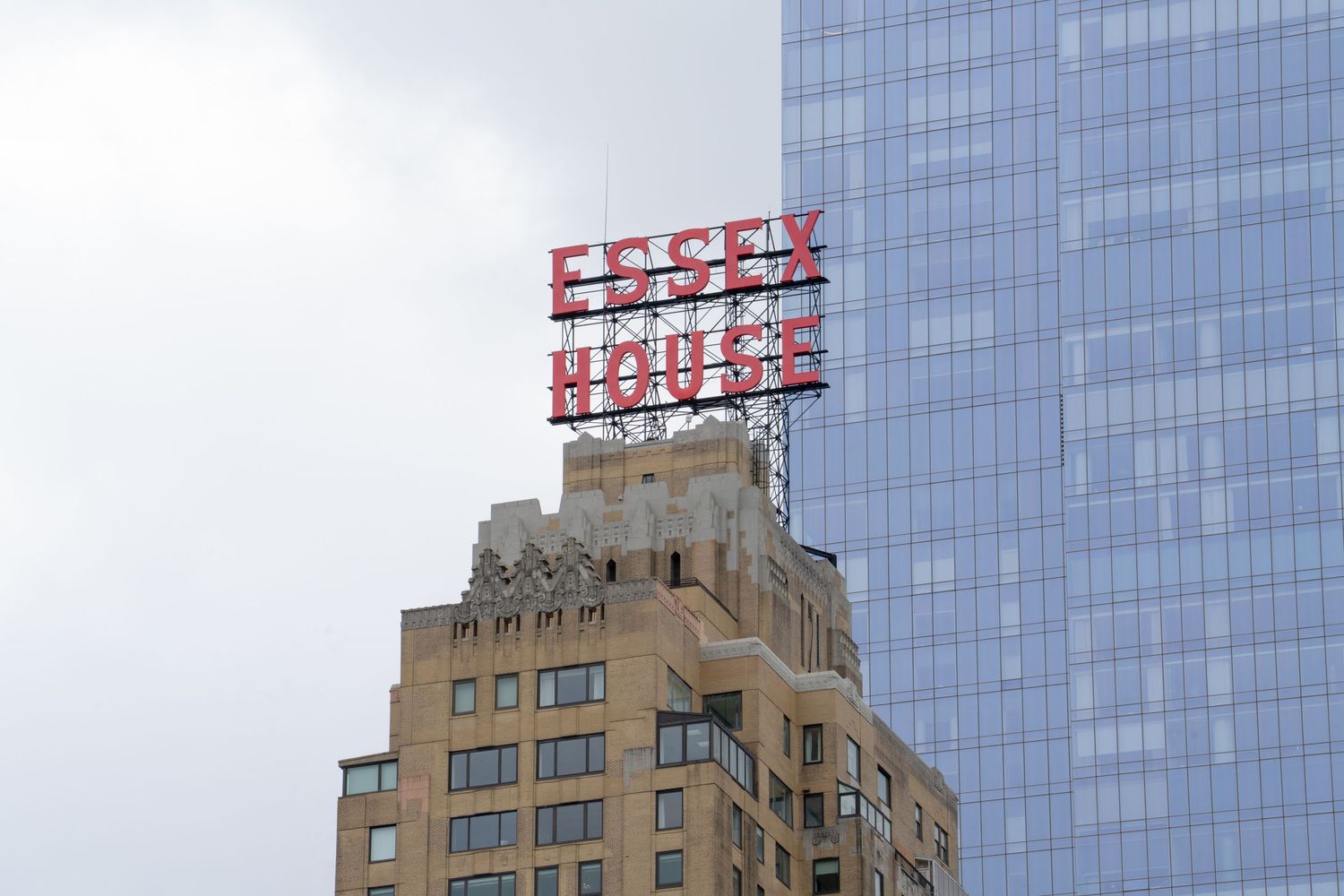 Modern glass skyscraper with art deco style buildings visible in New York City against blue sky.