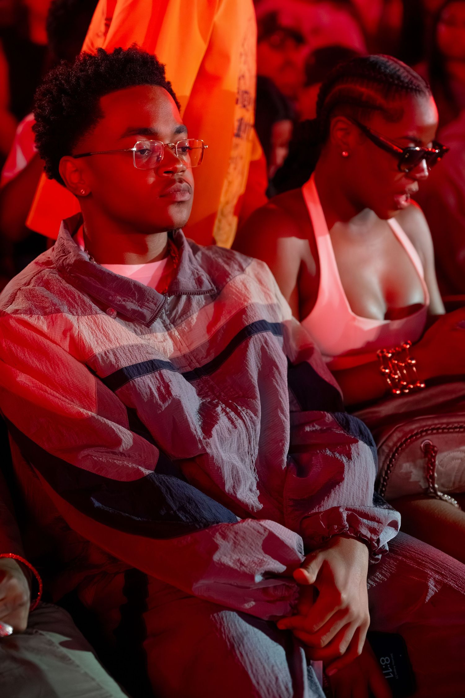People sit in red-lit theater seats during an event or performance.