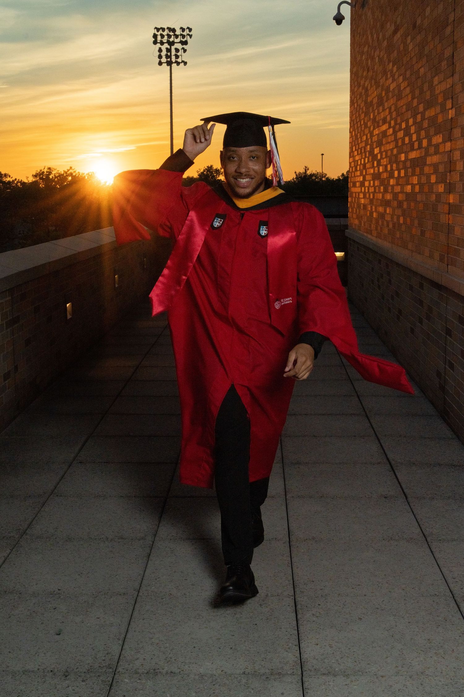 Sunset graduation photo with golden light streaming across concrete walkway.