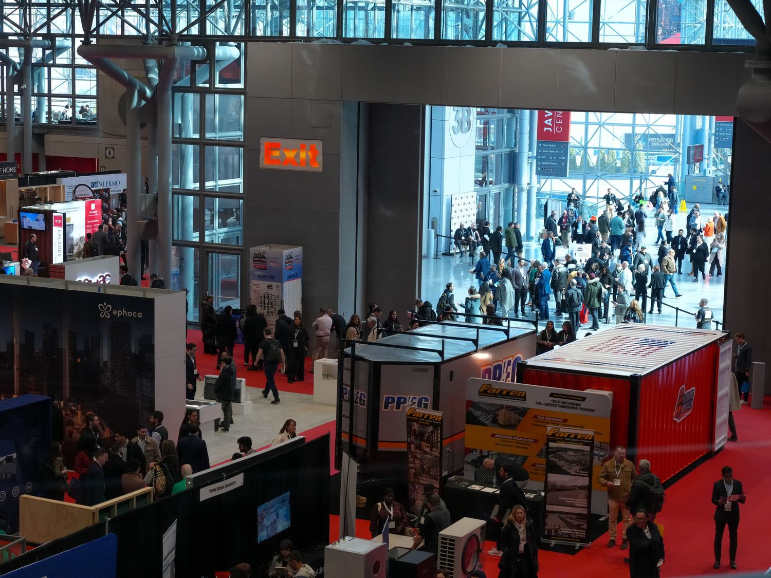 Aerial view of a busy trade show exhibition hall with colorful booths, red carpet aisles, and crowds of attendees.