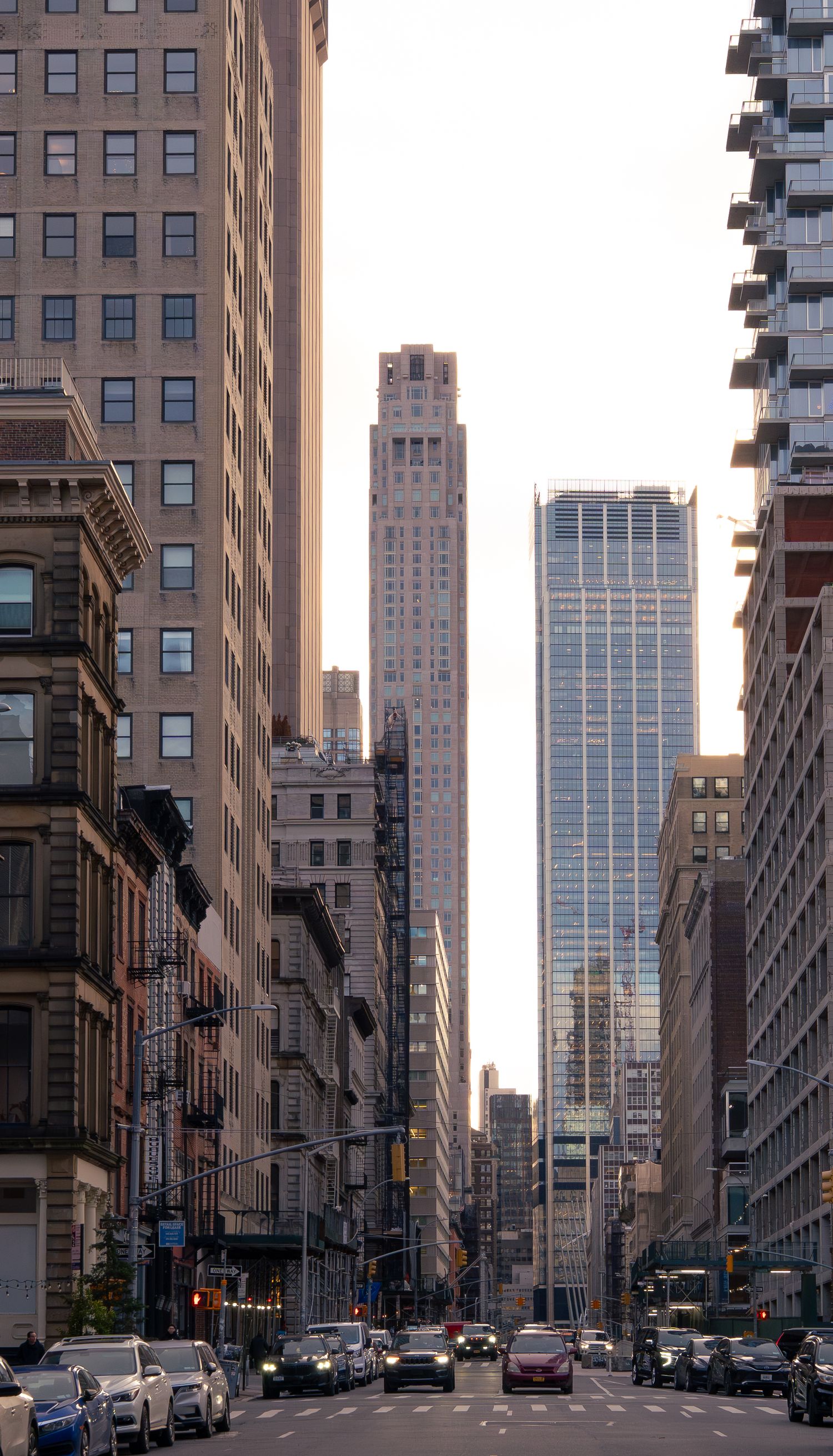 Urban street view of New York City with tall buildings and skyscrapers during golden hour lighting.