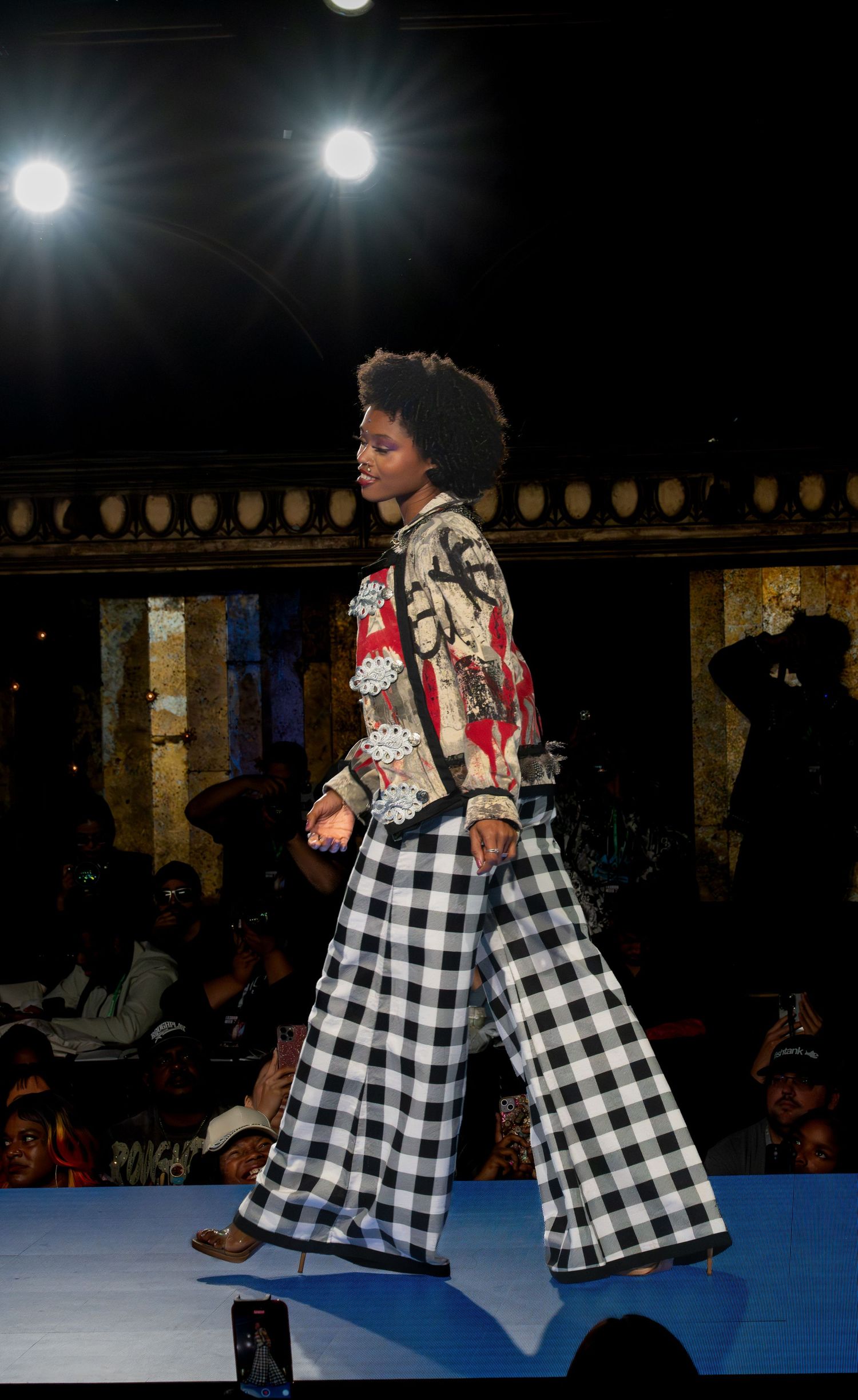 Models wearing matching black and white checkered dresses walk the runway.