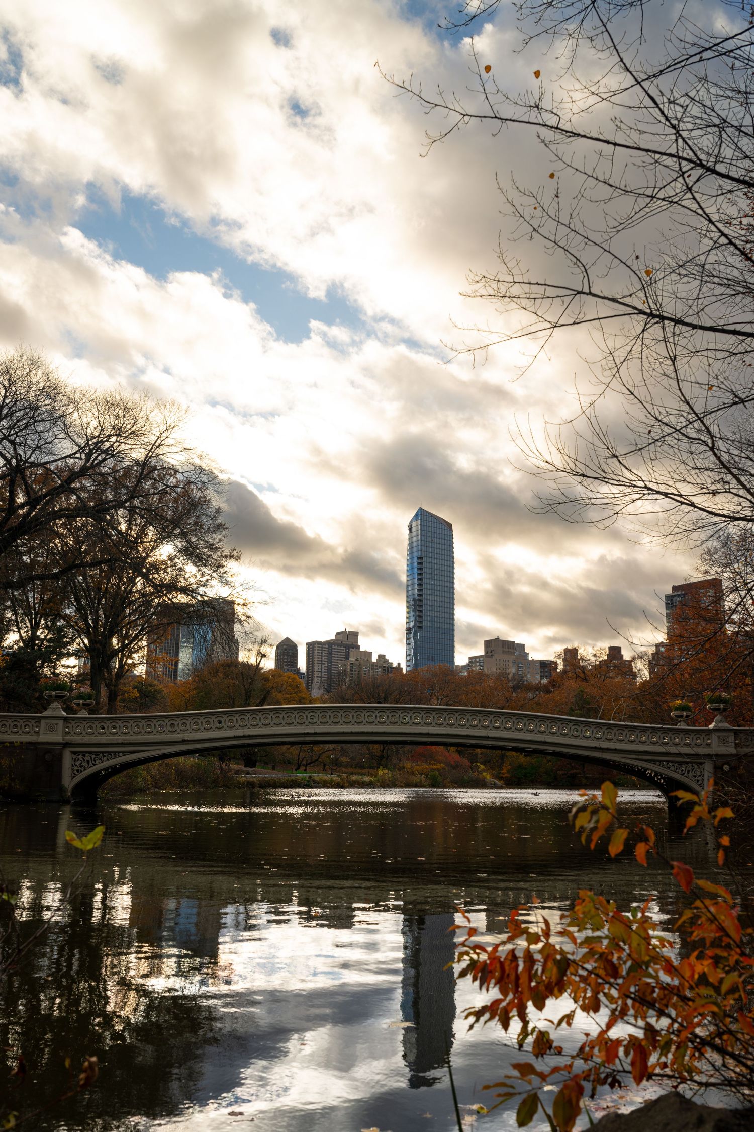Panoramic view of Central Park Lake with Manhattan skyline and autumn foliage at sunset.