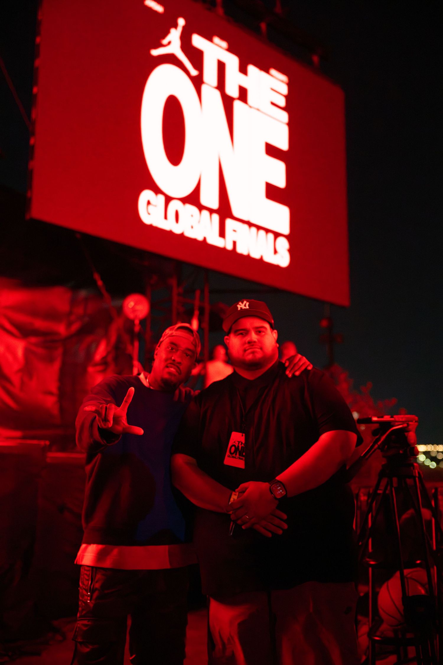Band performing on stage with red illuminated signage in background.