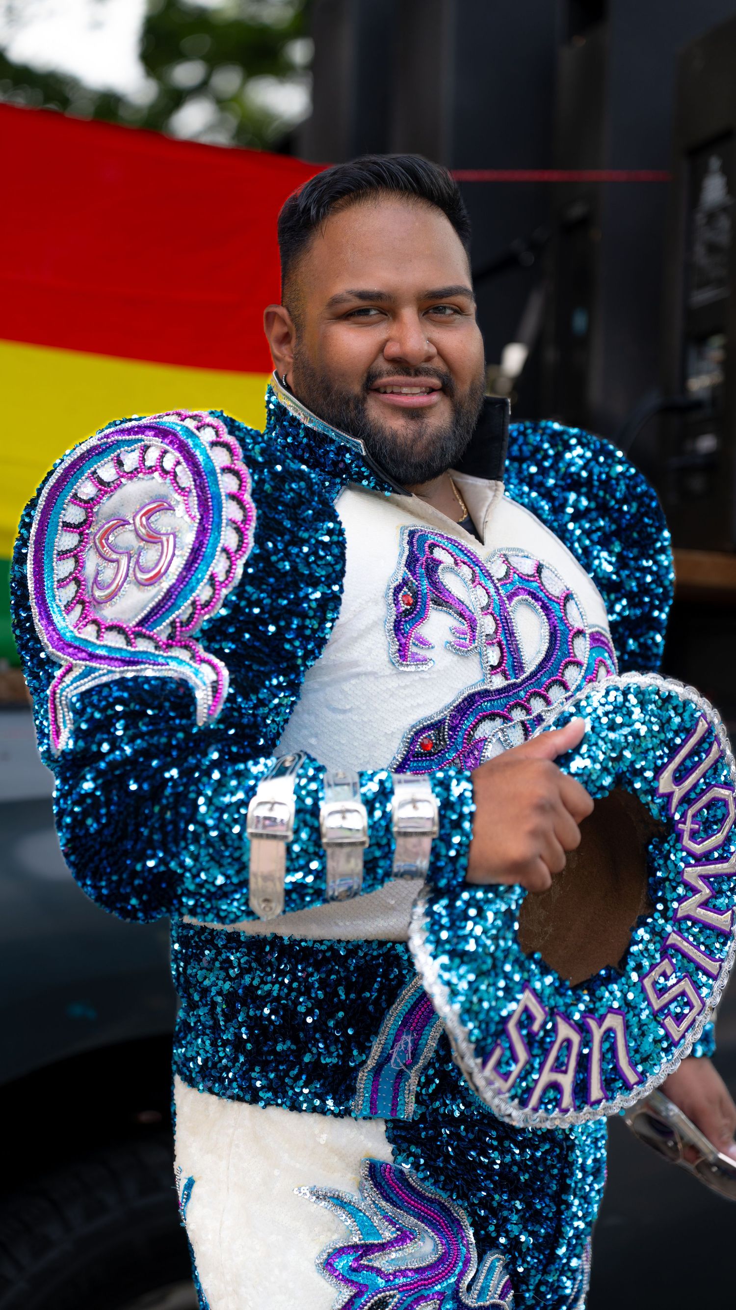 A performer wears an elaborate sequined costume with blue and purple designs.