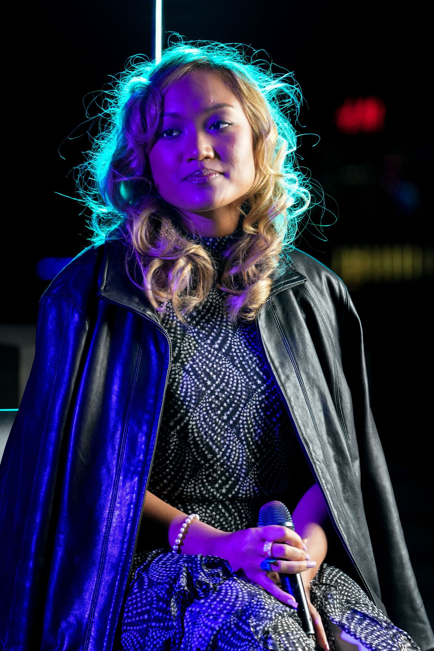 Performer in a sparkly dress illuminated by blue stage lighting during a concert performance.