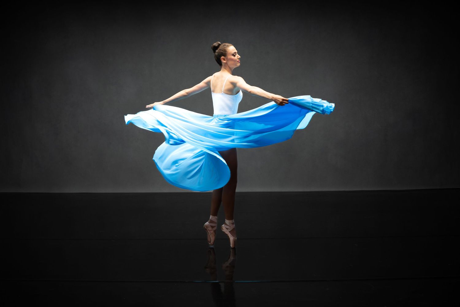 Modern dance performance featuring flowing blue fabric movement against black backdrop.