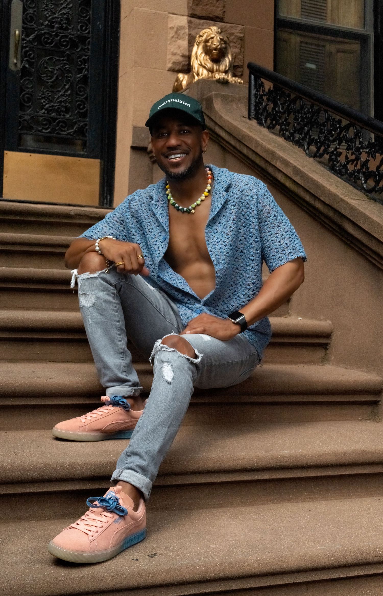 Person in blue shirt and jeans relaxing on urban brownstone steps.