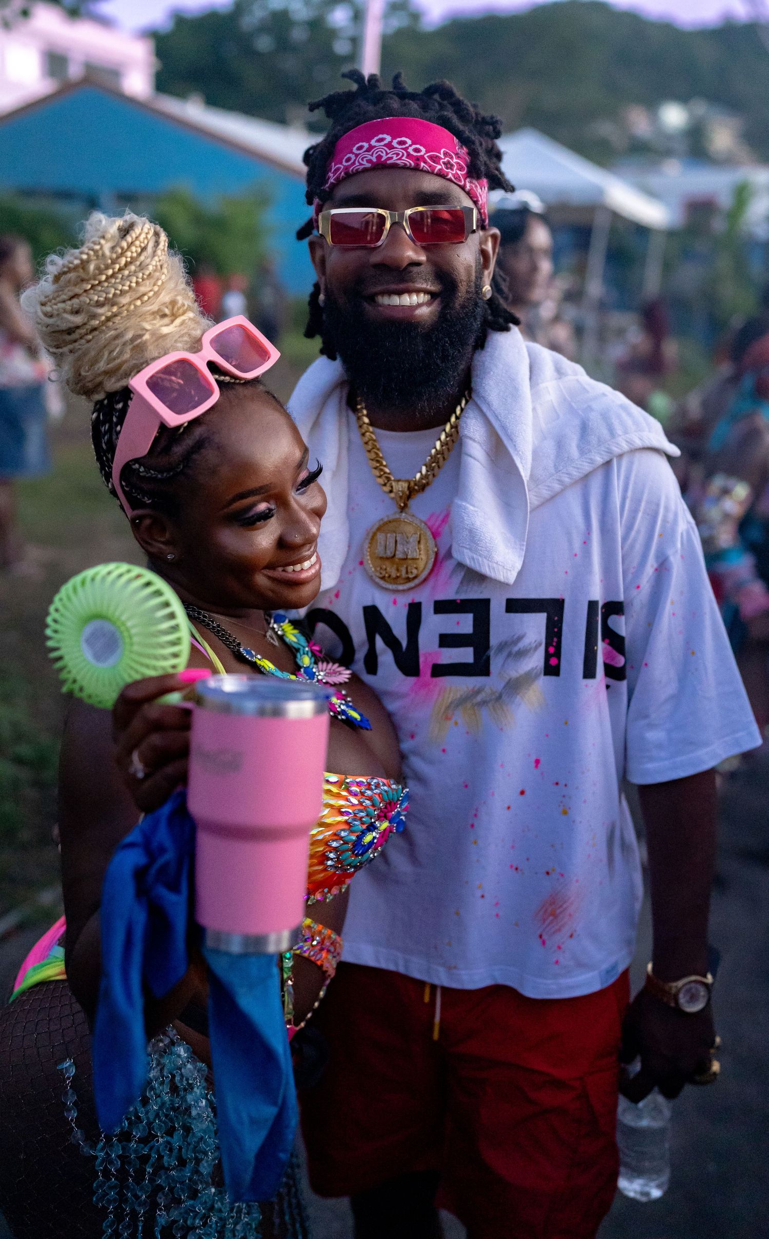 Festival attendees in colorful outfits enjoying a summer event with pink drinks and decorative fans.