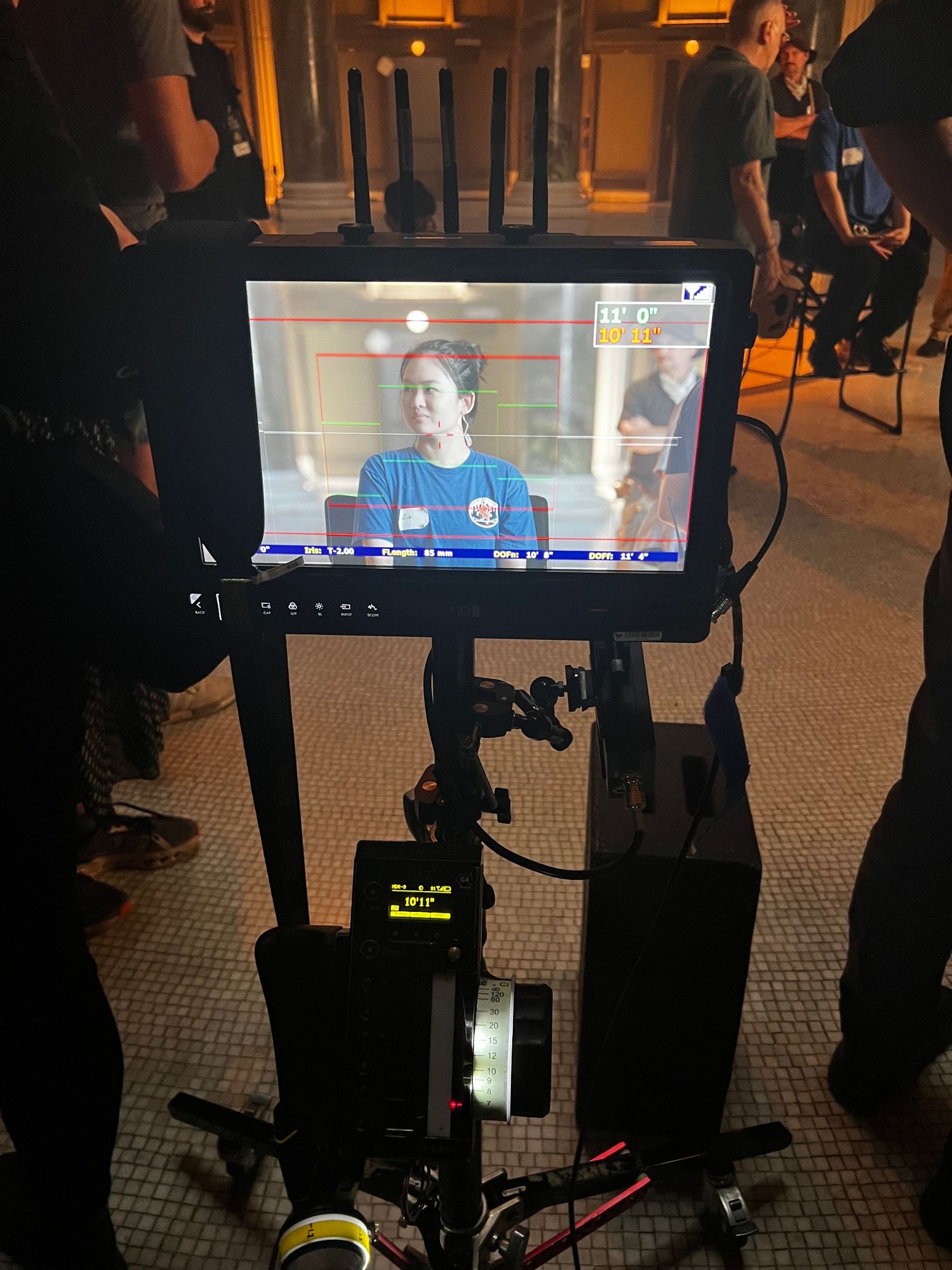 Behind-the-scenes view of a television production setup with multiple monitors and camera equipment in a dark room.