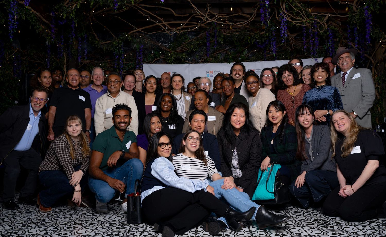 Large group photo of attendees at an indoor event with dark lighting.