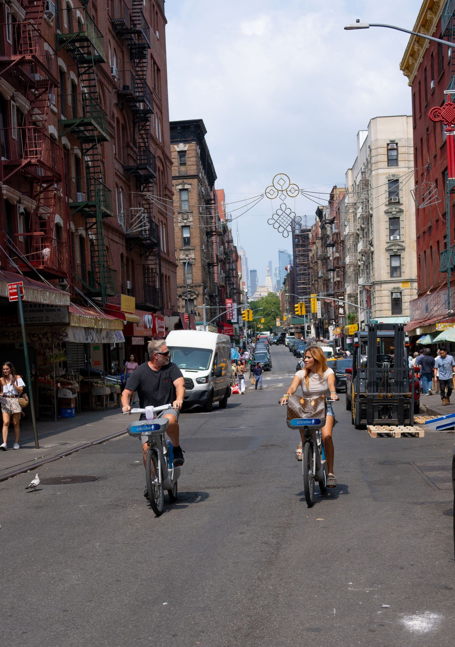 Street scene in New York City with cyclists and pedestrians moving through historic neighborhood.