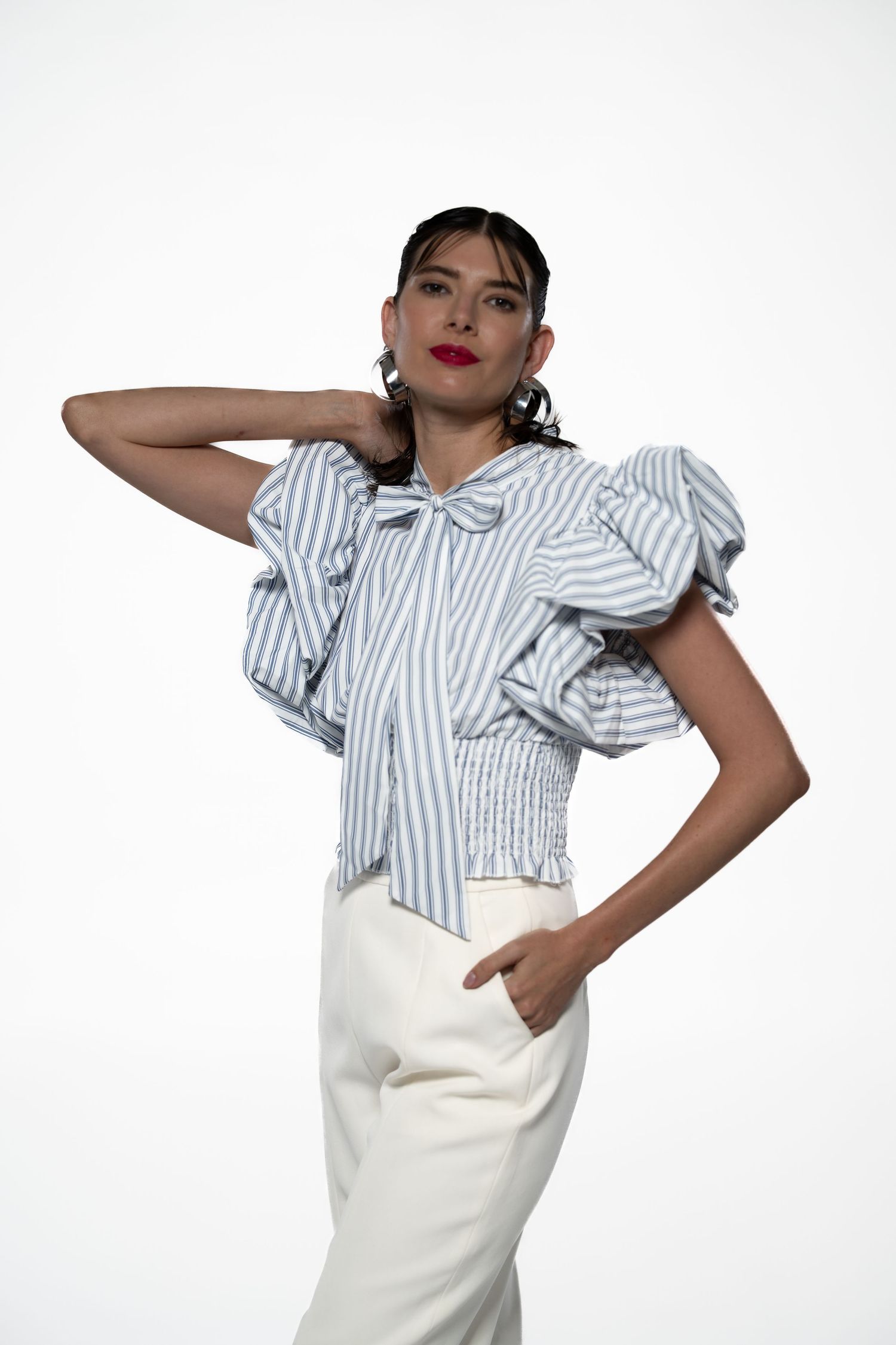 Fashion model wearing striped ruffled top and white pants strikes playful poses.