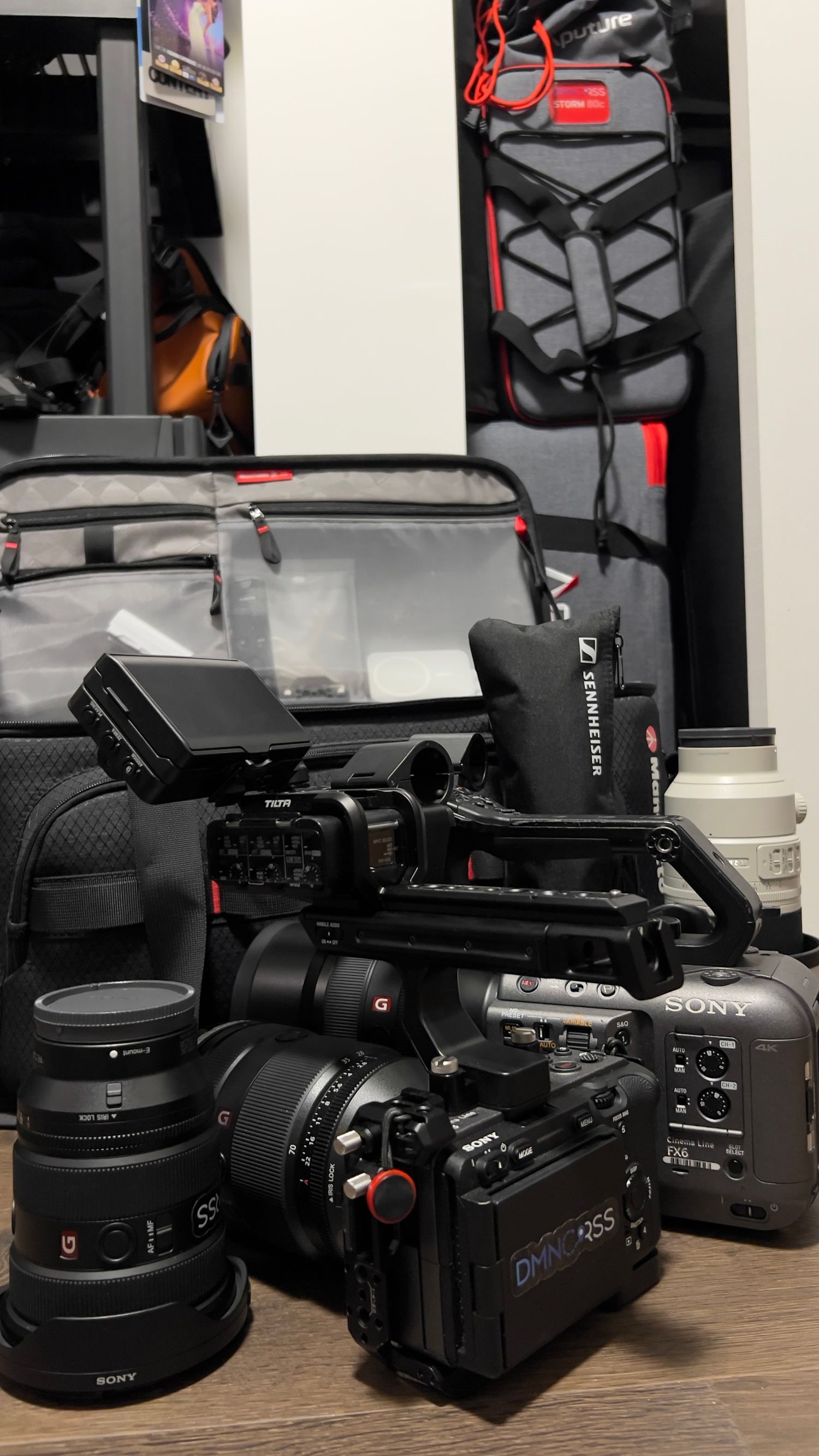 Professional Sony video camera setup with multiple lenses and accessories arranged on wooden surface.