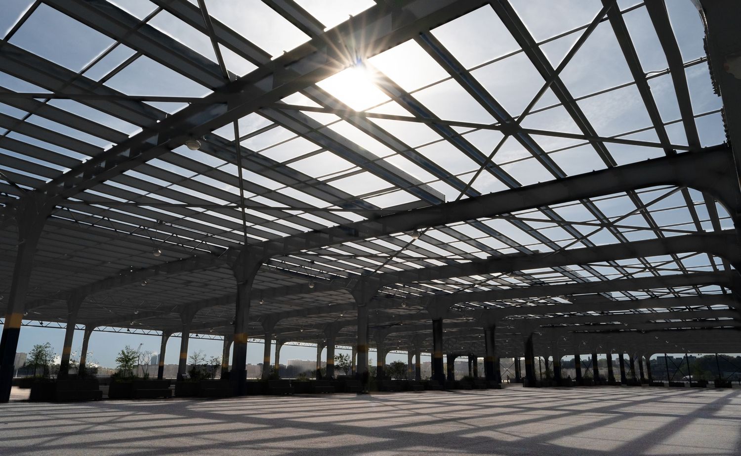 Industrial steel roof structure creating dramatic shadows in sunlight.