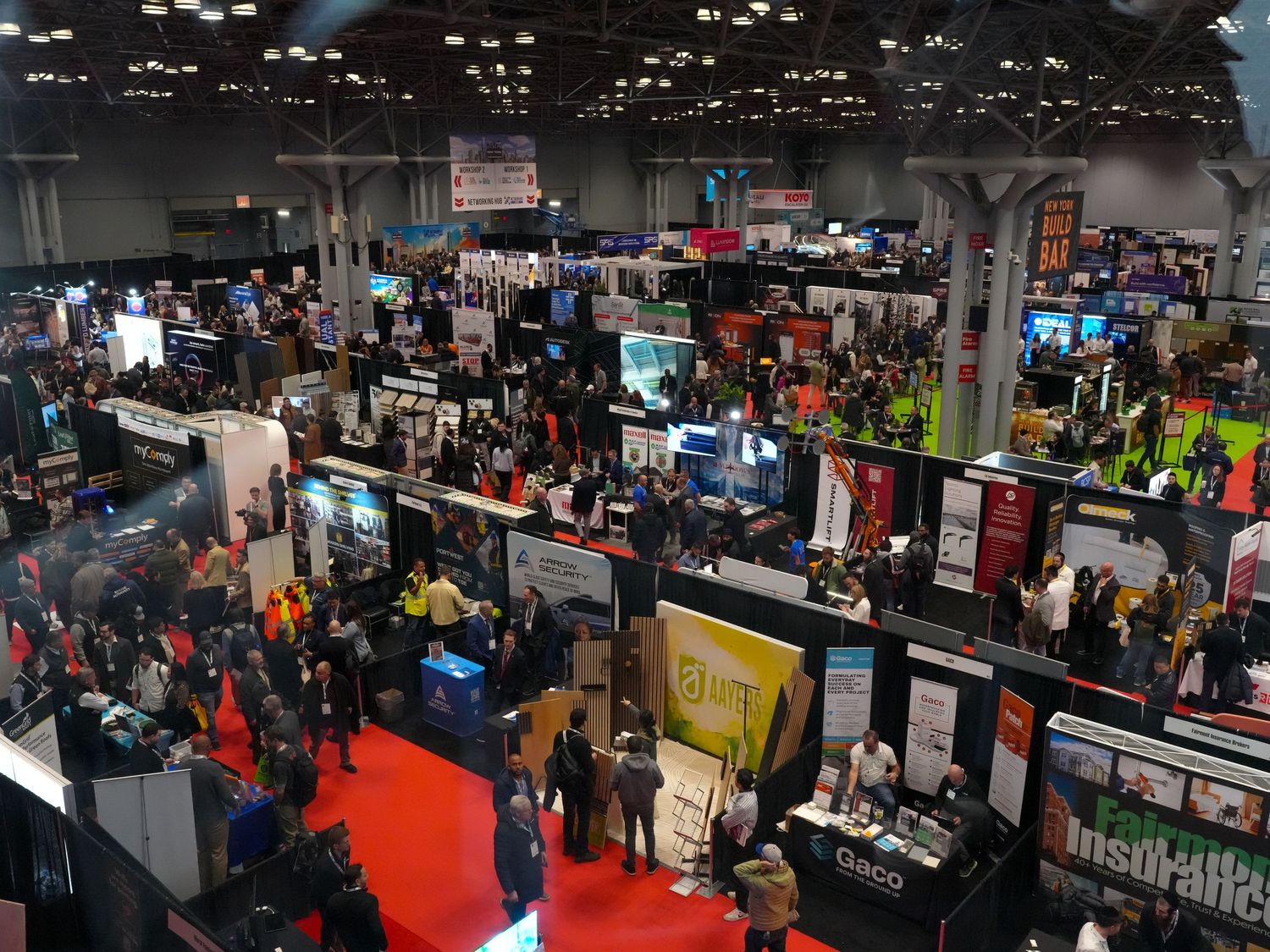 Aerial view of a busy trade show convention floor with numerous vendor booths and crowds of attendees.