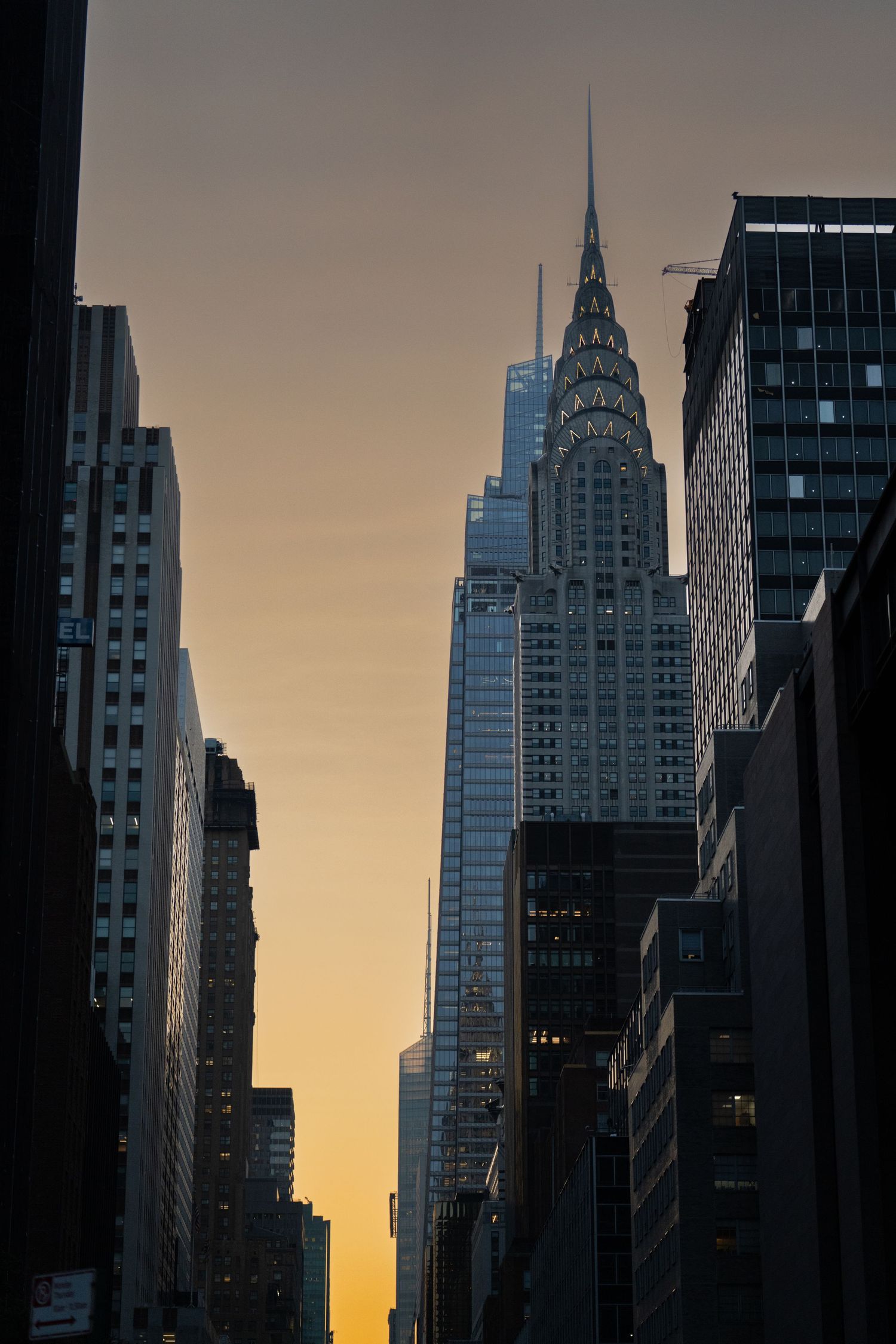 Art deco skyscrapers including the Chrysler Building silhouetted against golden sunset sky in Manhattan.