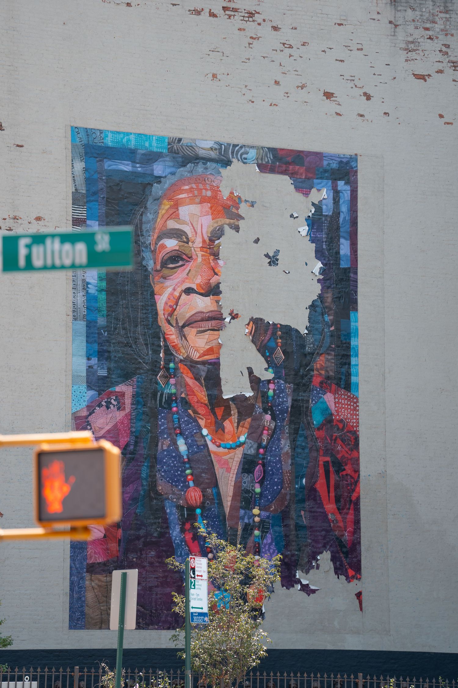 Colorful street art mural on a gray wall showing abstract portrait with vibrant blue and orange tones.